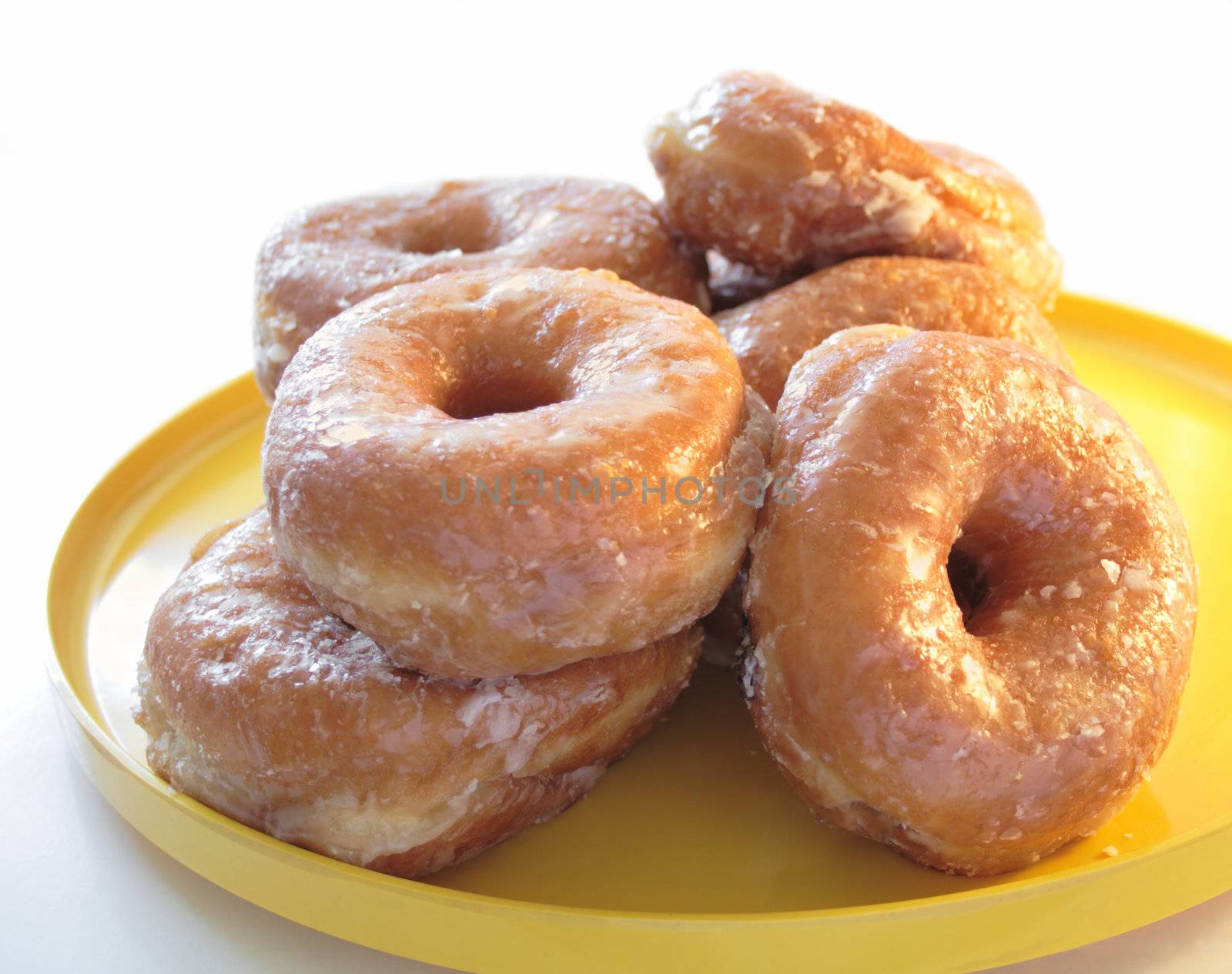 glazed yeast doughnuts on a yellow plate