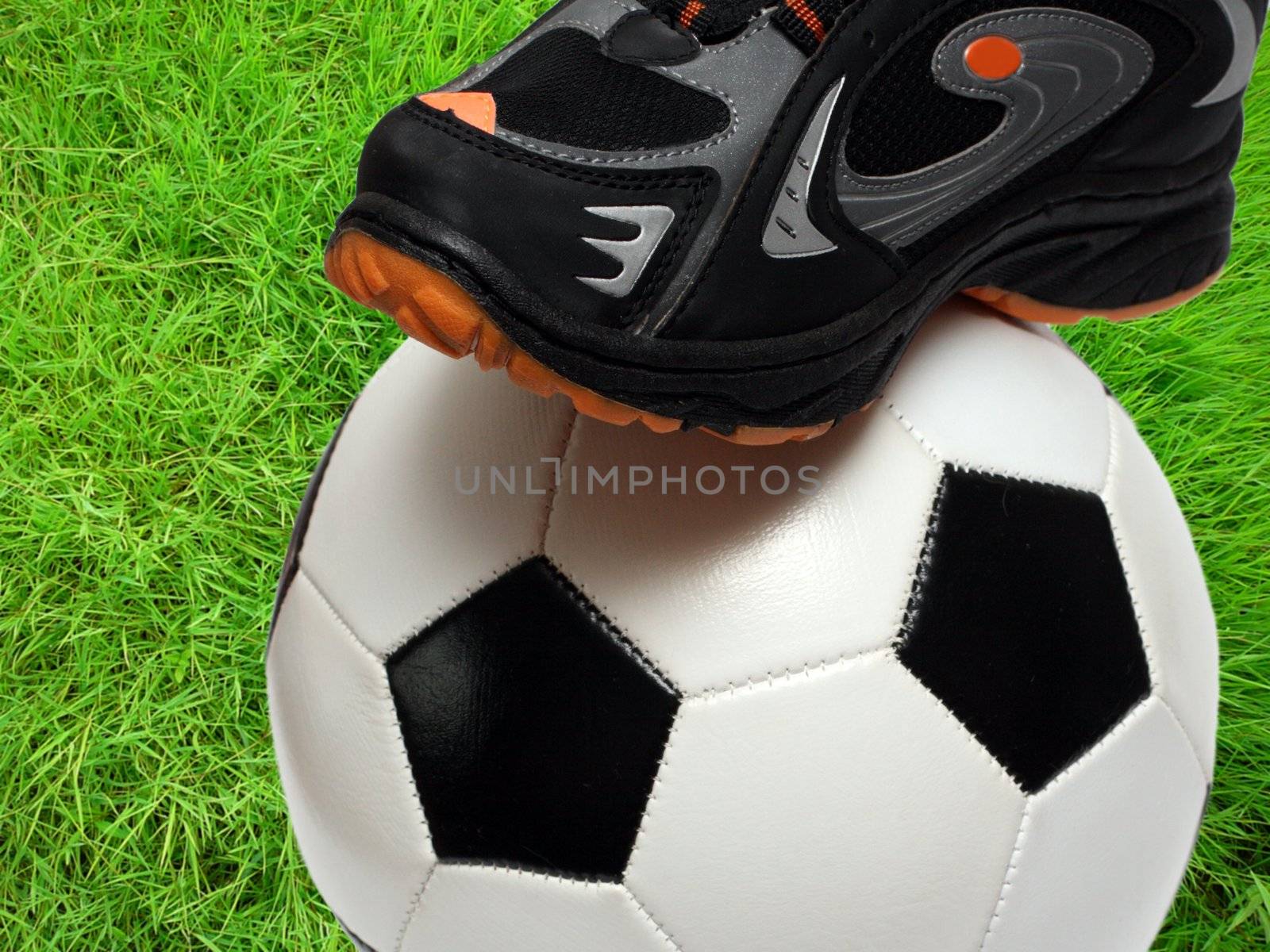 football shoe and soccer ball close-up over green grass field