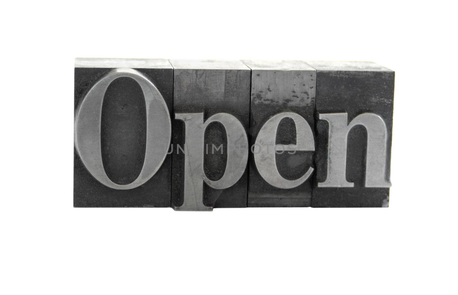 old, ink-stained metal letterpress type spells out the word 'Open' isolated on white