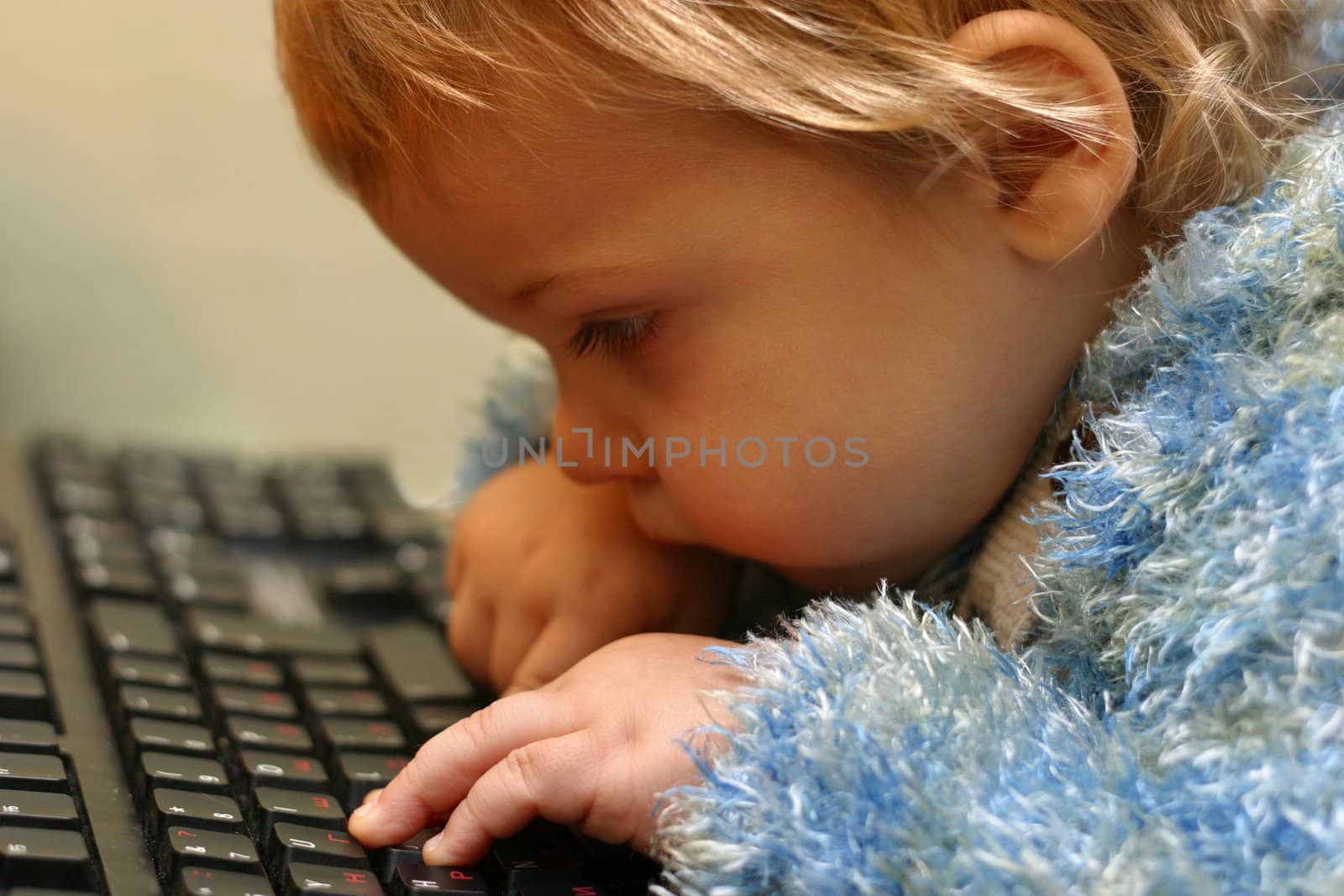The little boy considers keys of the keyboard