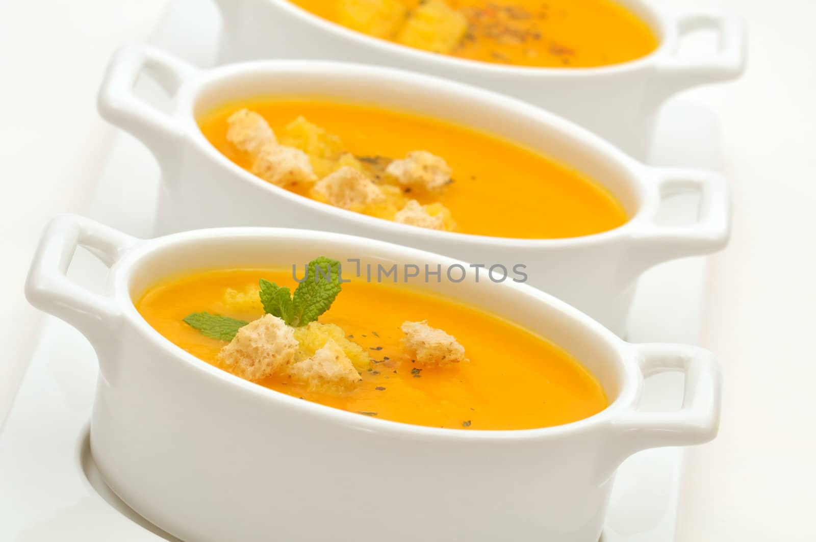 Carrot creamy soup served in small ceramic bowls