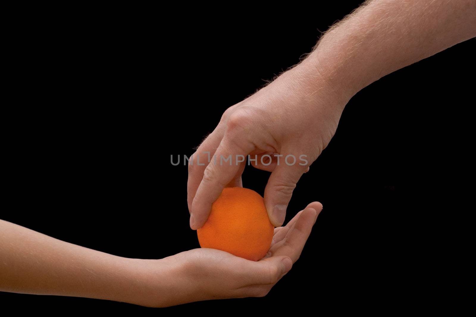 an isolated over black image of a caucasian man giving a caucasian child an lush juicy looking Orange.