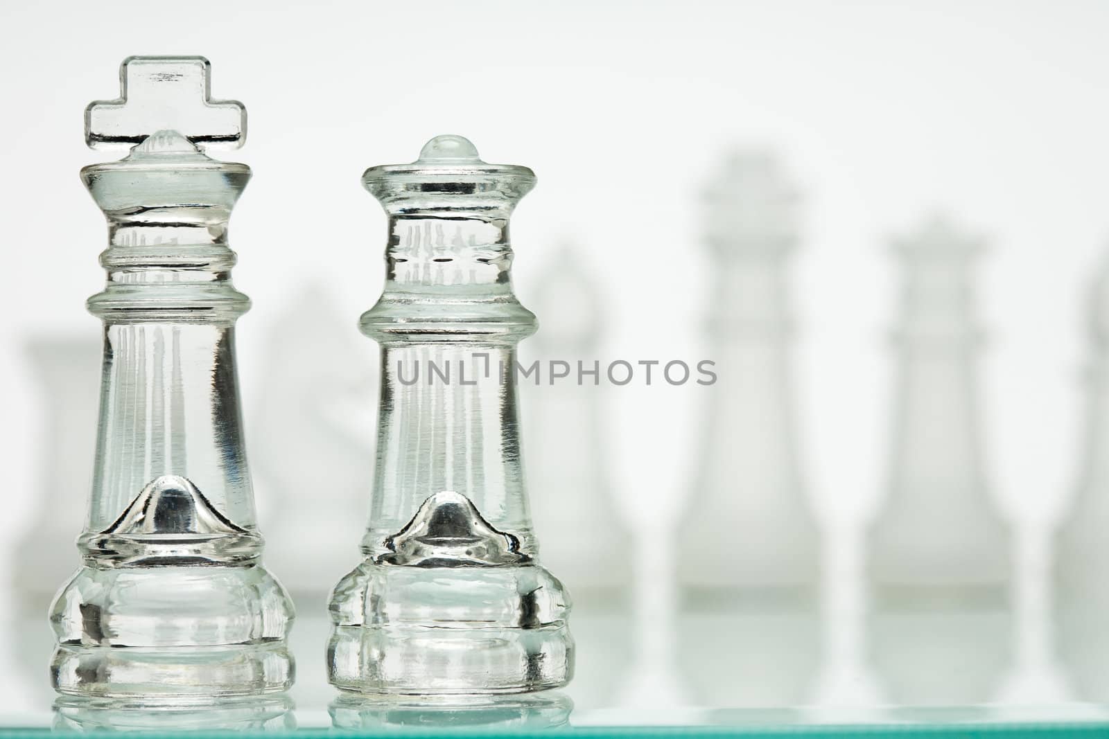 Transparent chess game on a white background. Line players in the background, blurred, over the shoulder of Kings and Queens sharp