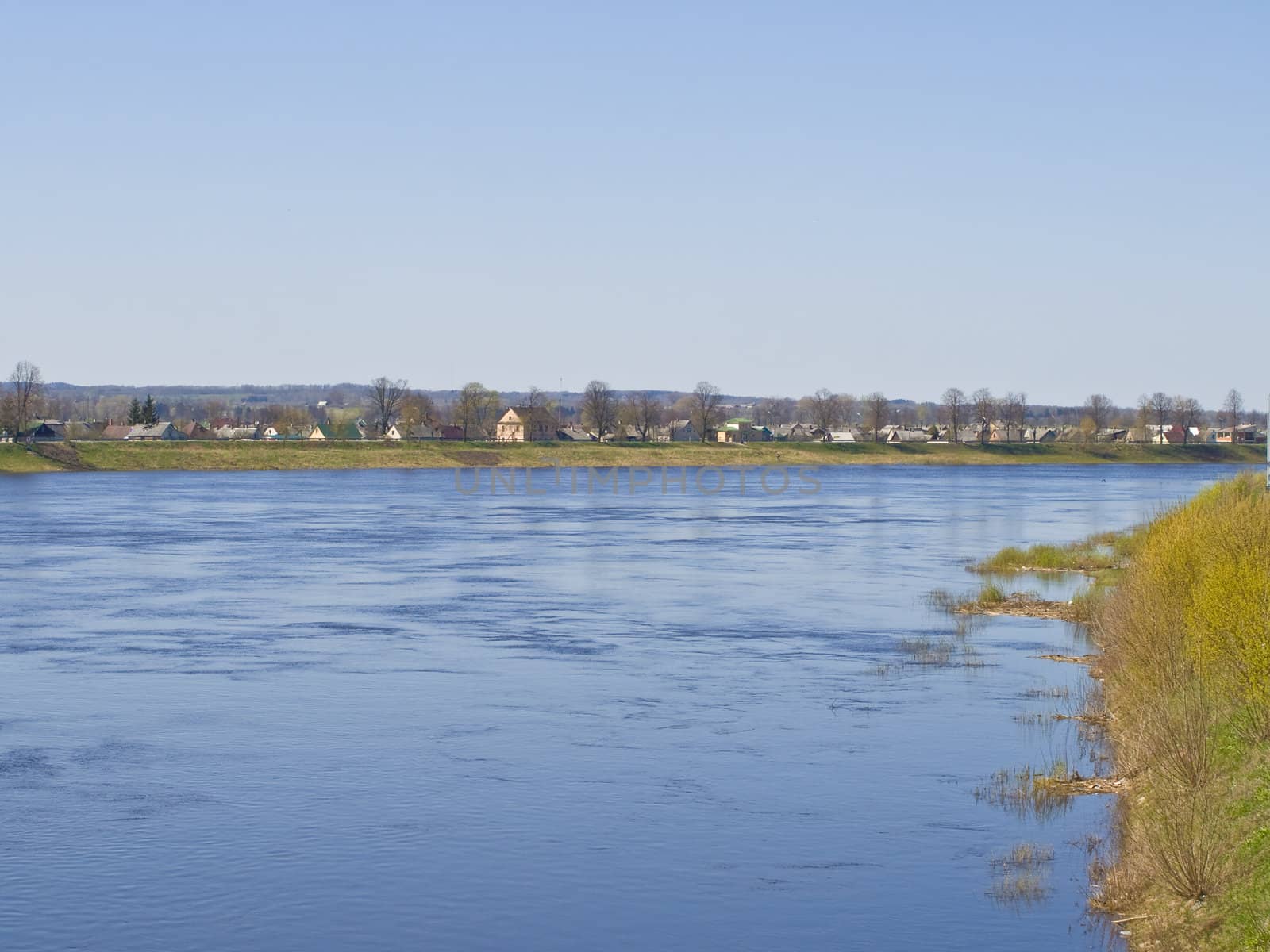 blue river with houses at the brinks with grass