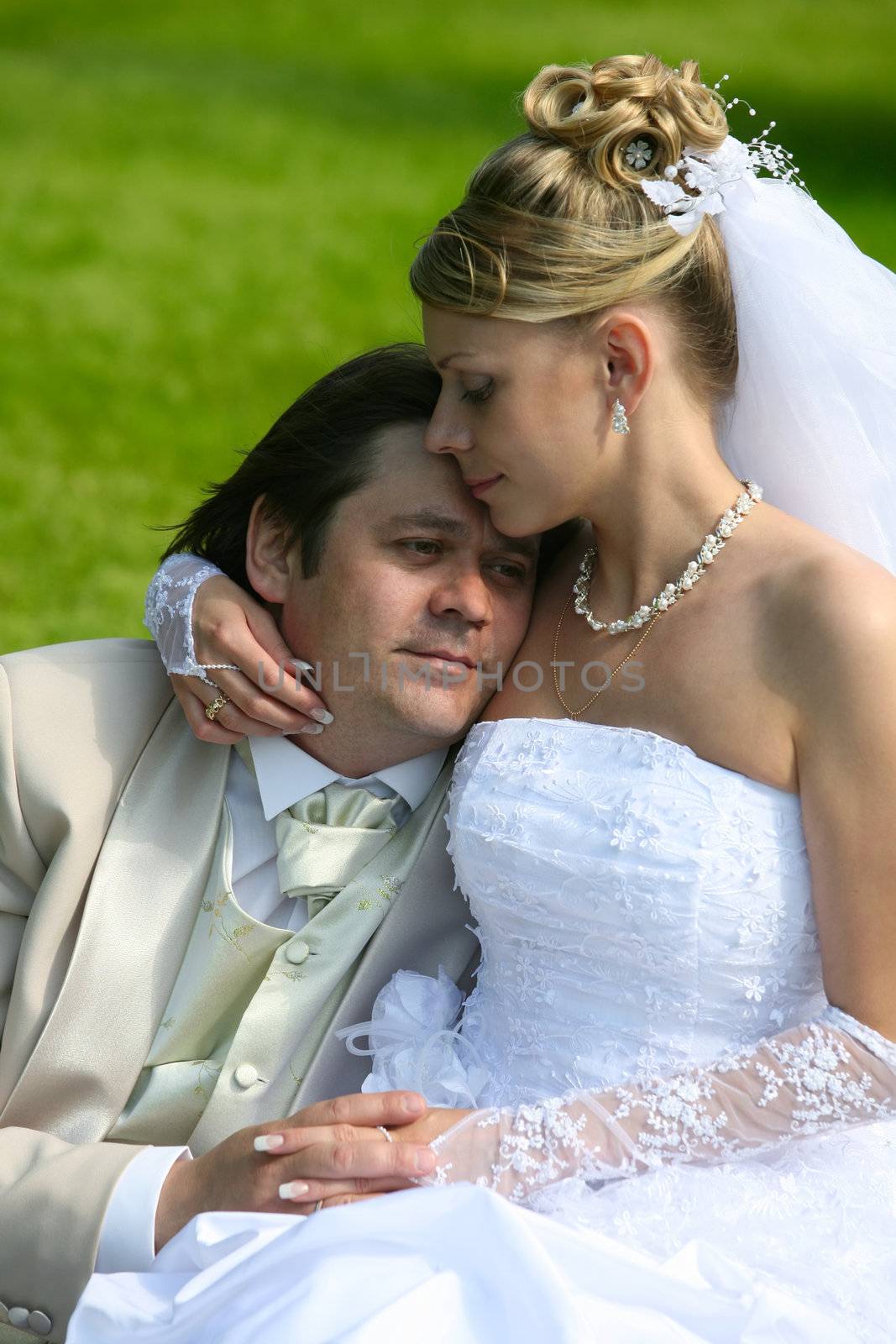 Recently married pair sits on a grass in park