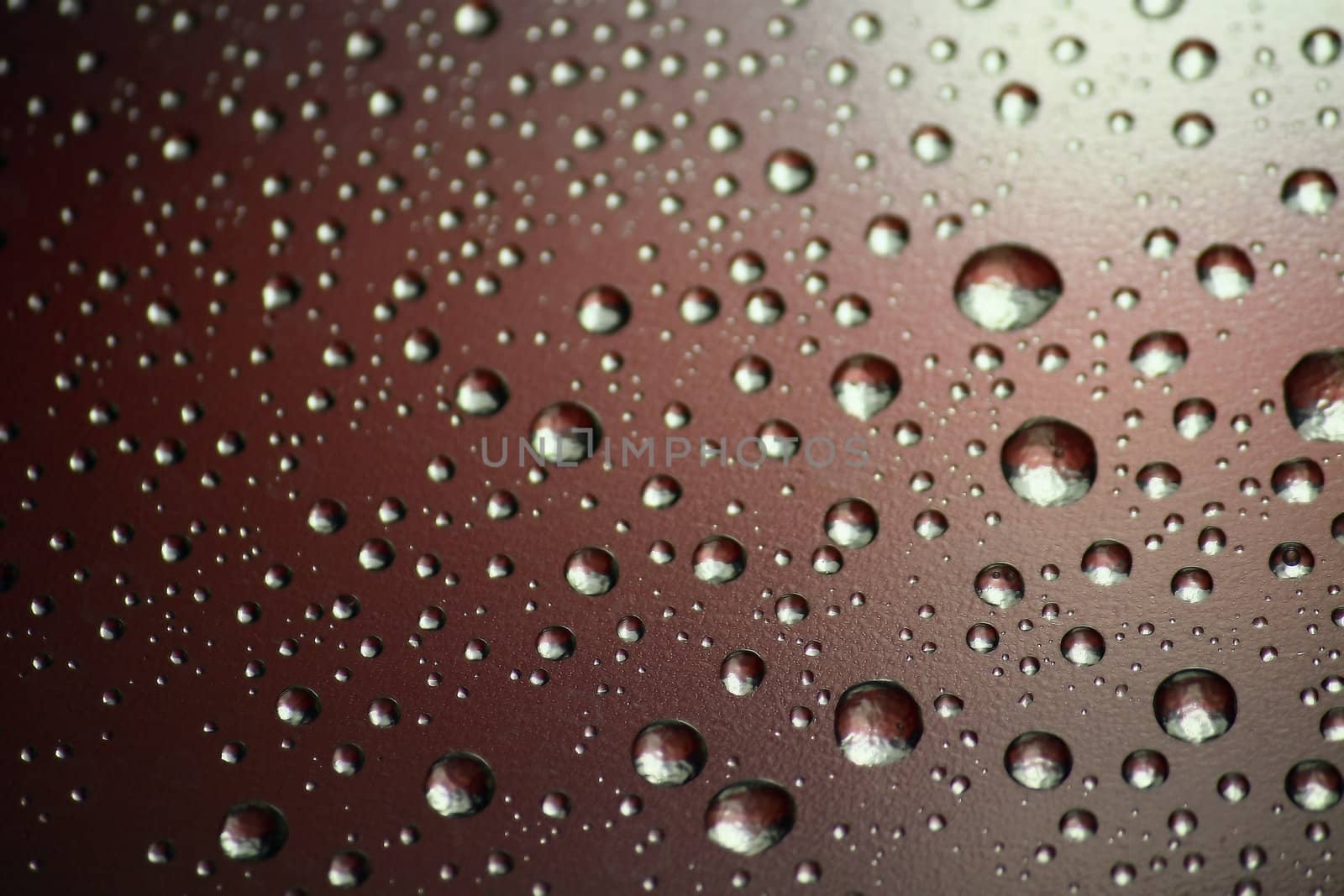 We see an unusual background. These are multi-colored drops of water on a surface.