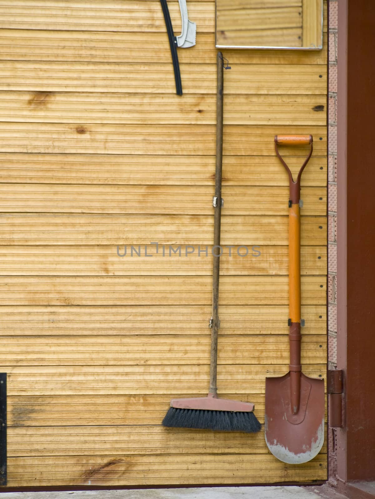 Domestic tools shovel and broom at the wooden door