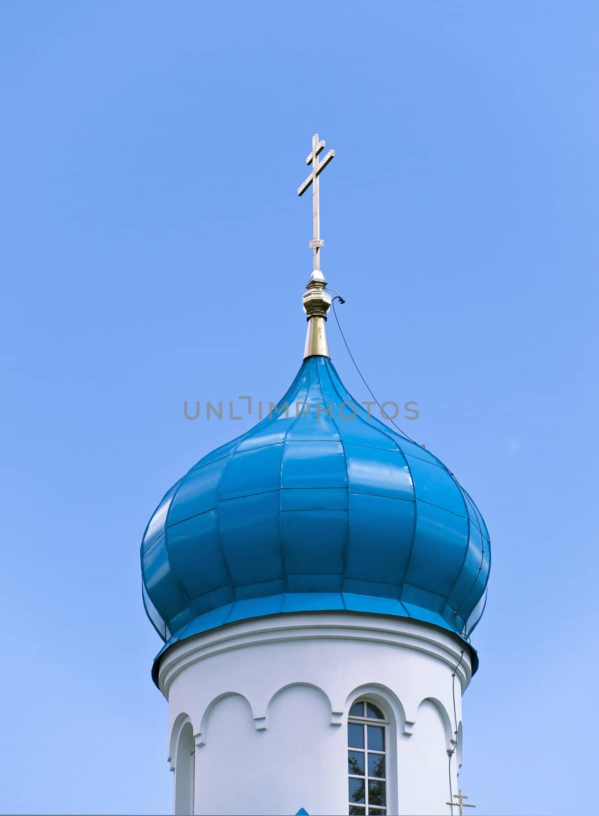 Blue cupola of the church with gold cross against the blue sky