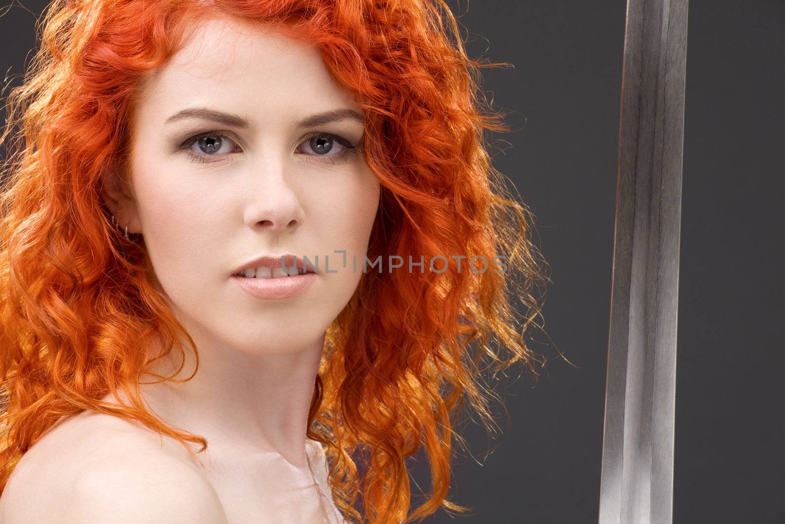 lovely redhead with medieval sword over grey