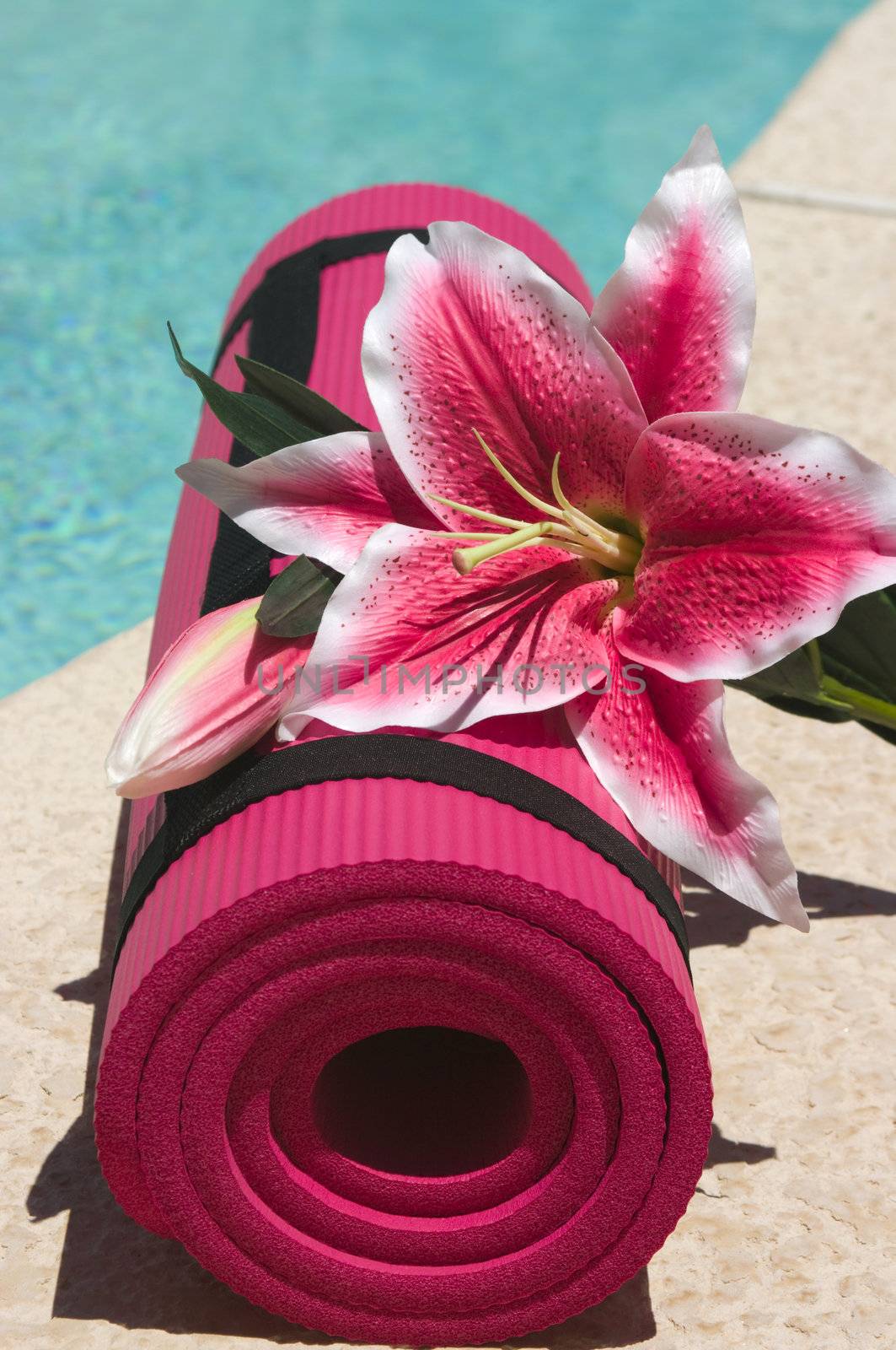 Yoga mat and a beautiful lily near a pool
