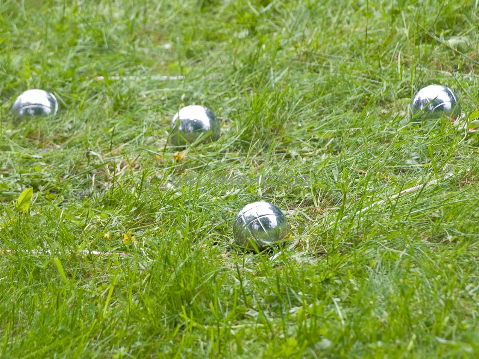 four shiny metall balls on the green grass