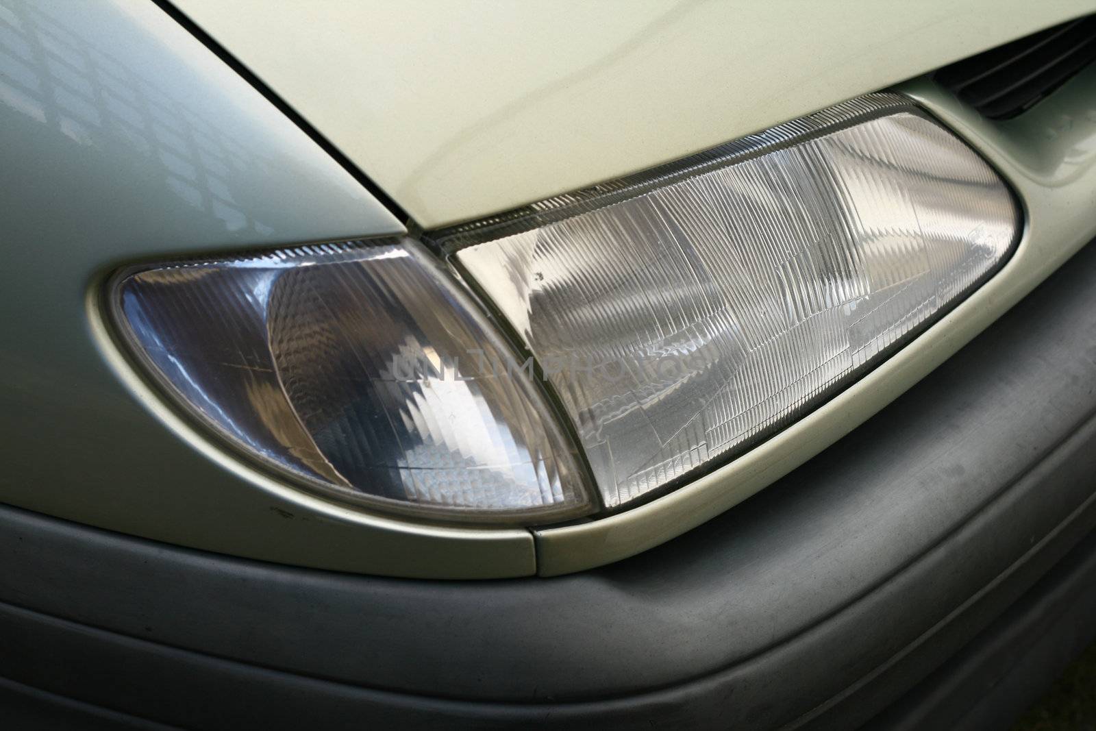 car front light and wing with black bumper of a green car