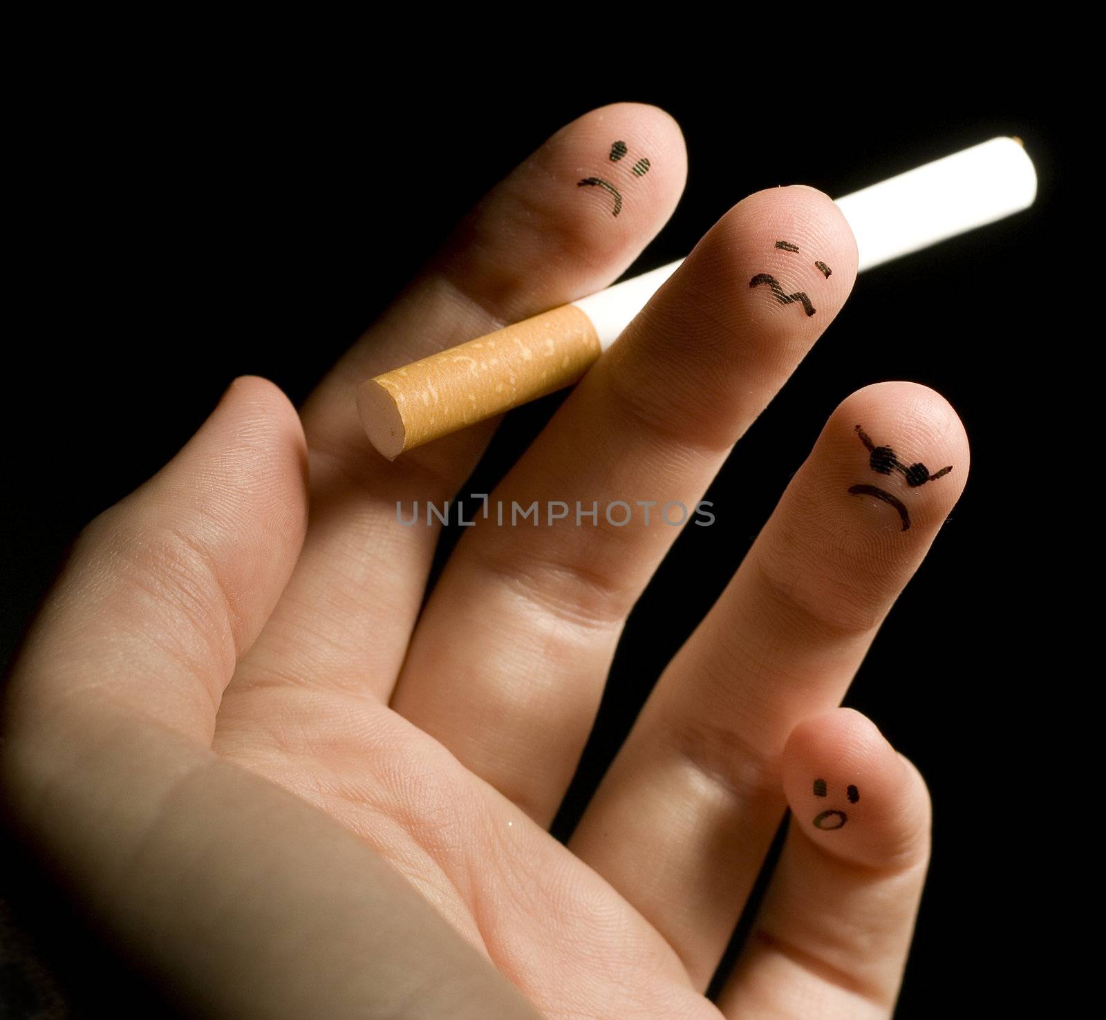 
Fingers holding cigarette. Sad smiley painted on fingertips. Conception of addiction and anti-smoking.