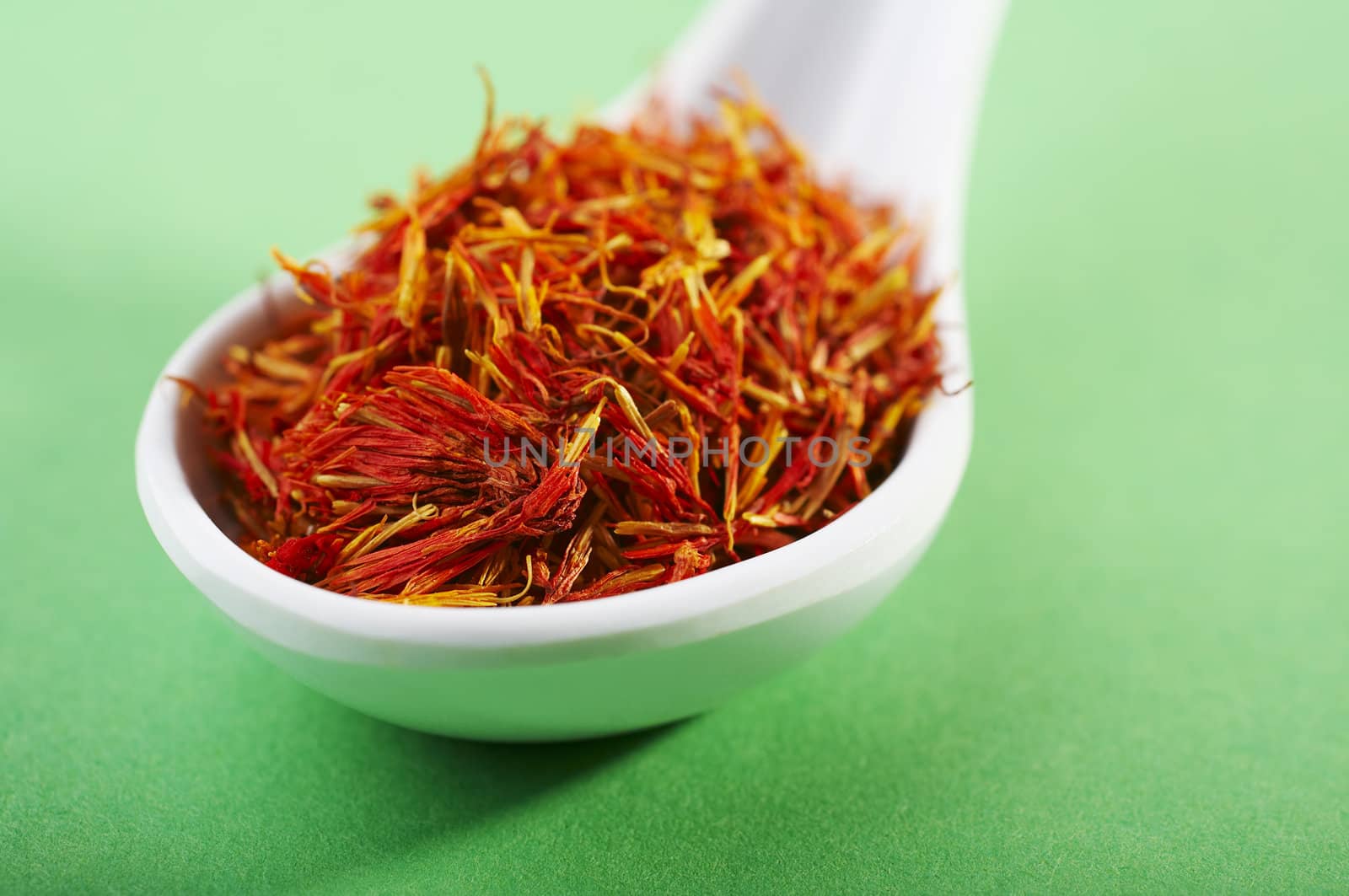 spoon of dried saffron on green background
