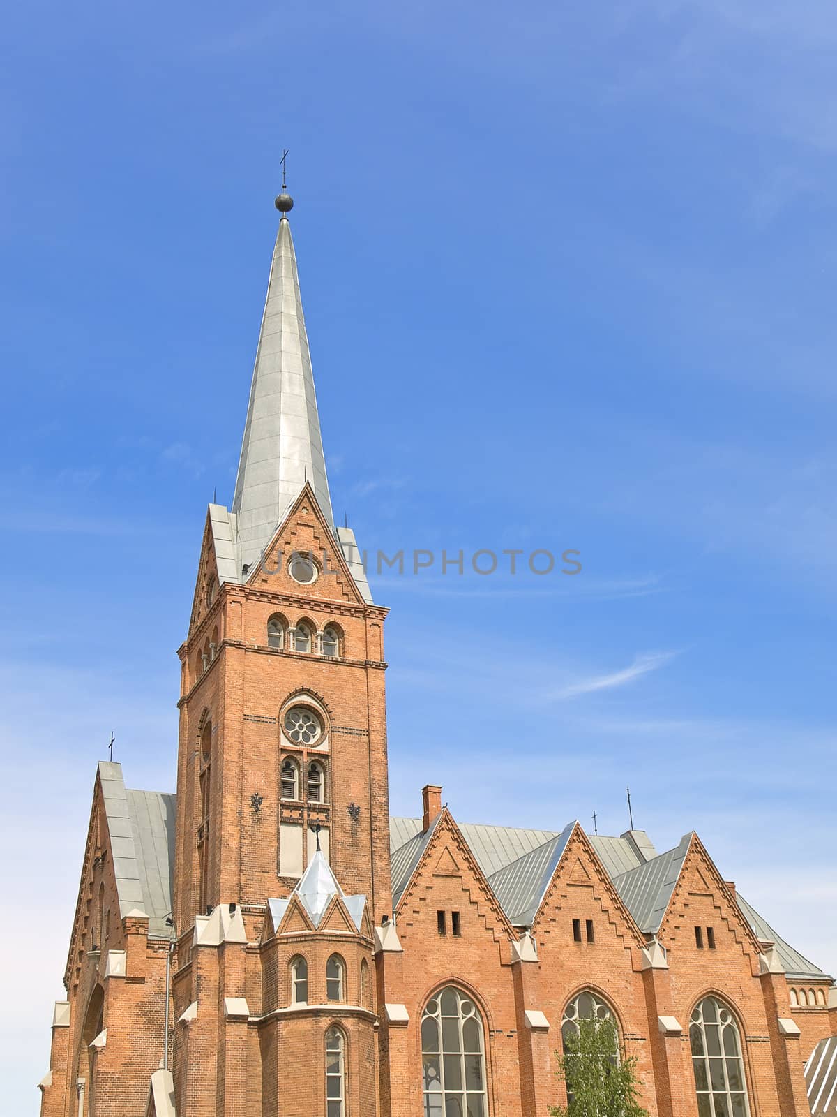 red brick Church against the blue cloudy sky 