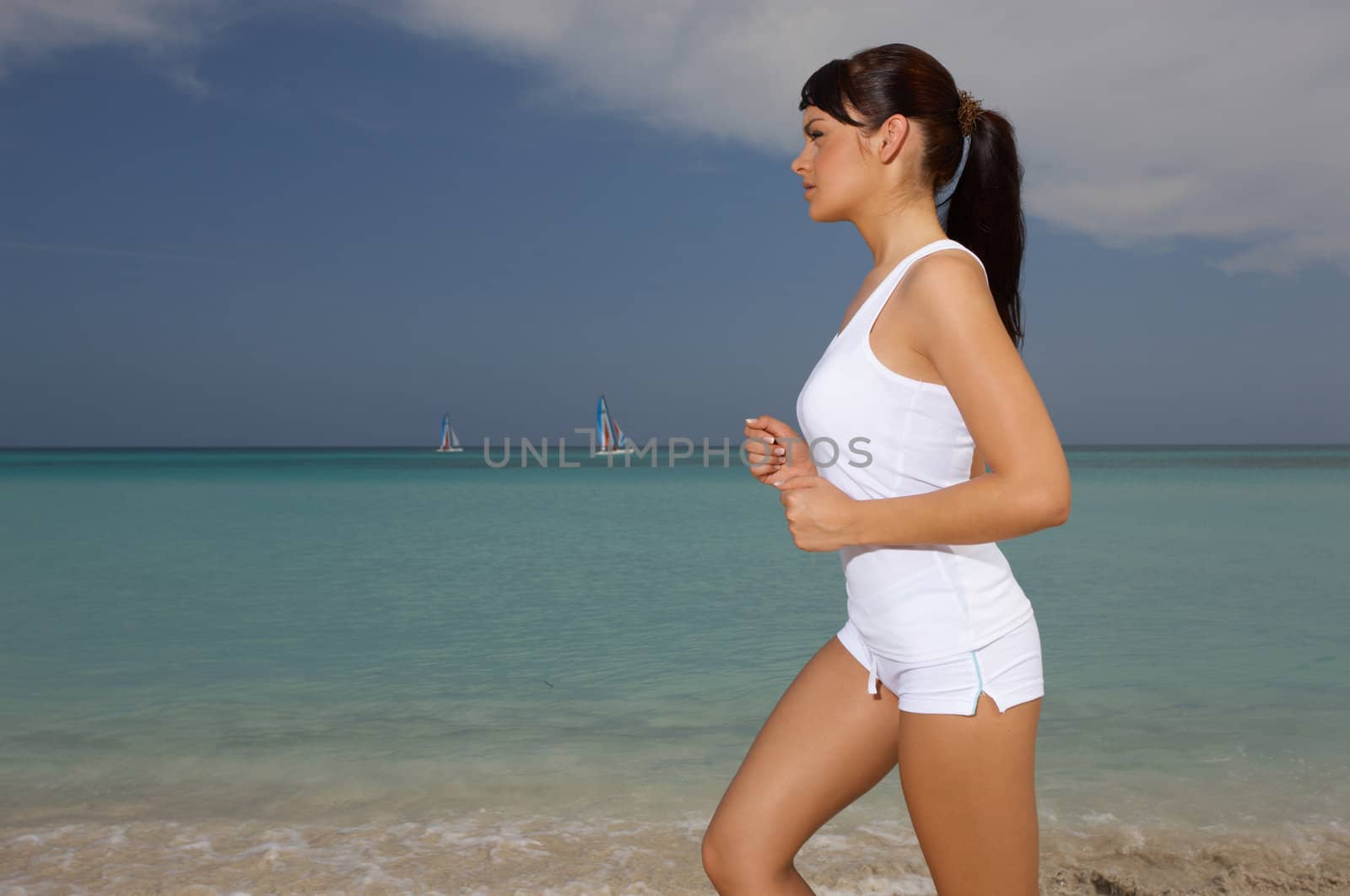 Young beautiful woman during fitness on sea beach 