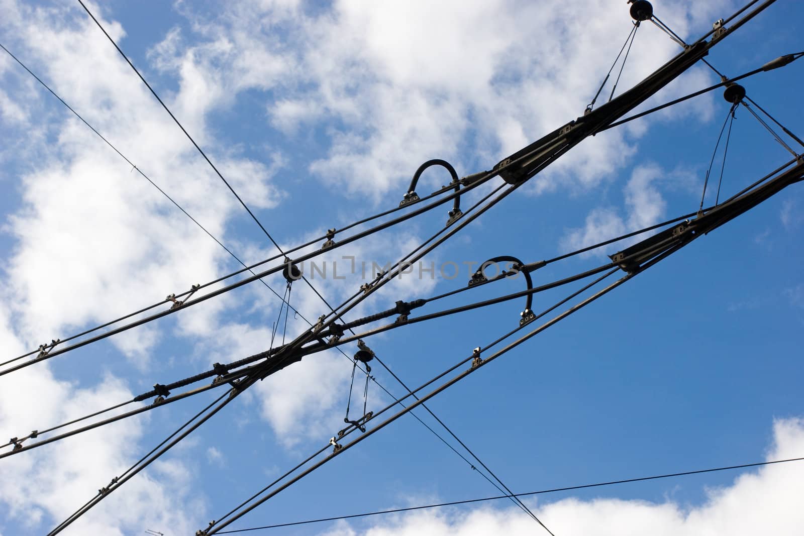 Suspended tramway power cables against blue sky with clouds