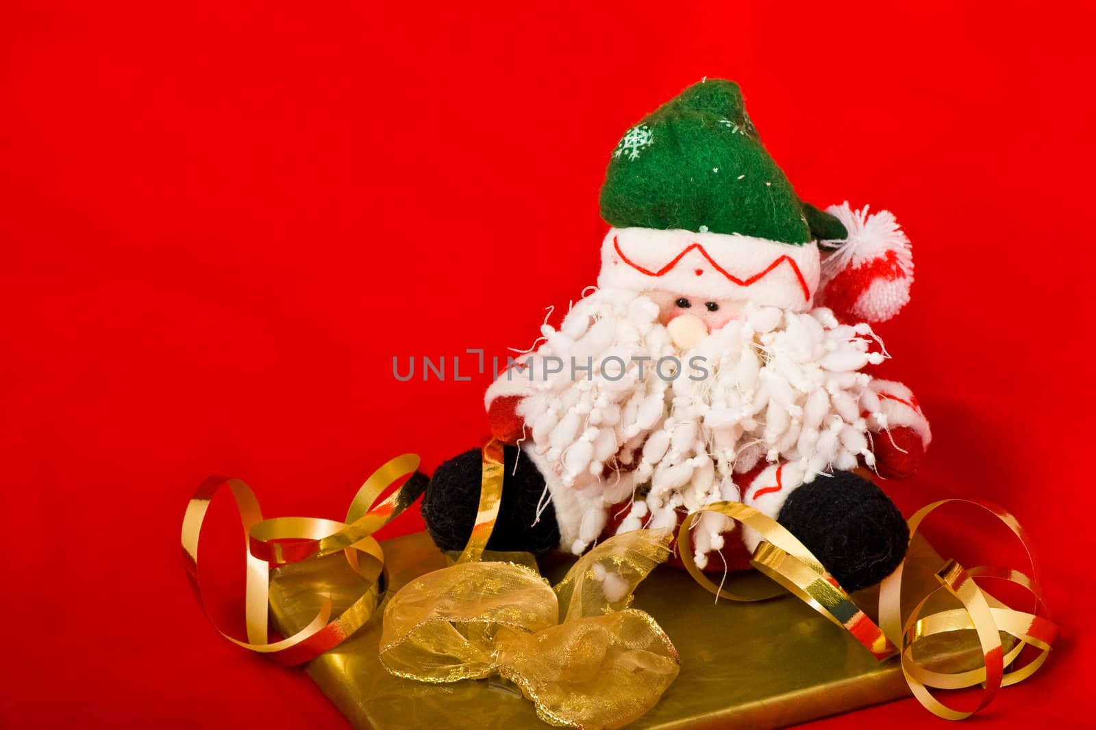 Christmas Santa puppet and the golden gift box with ribbon on red