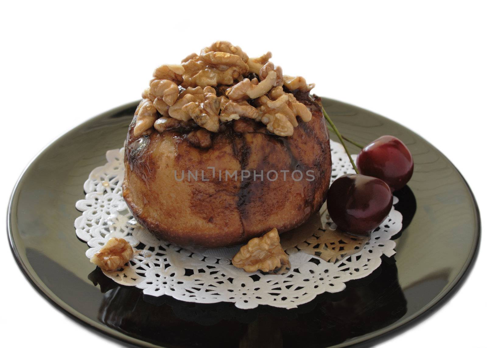a sweet sticky bun with walnuts and fresh cherries on a black plate