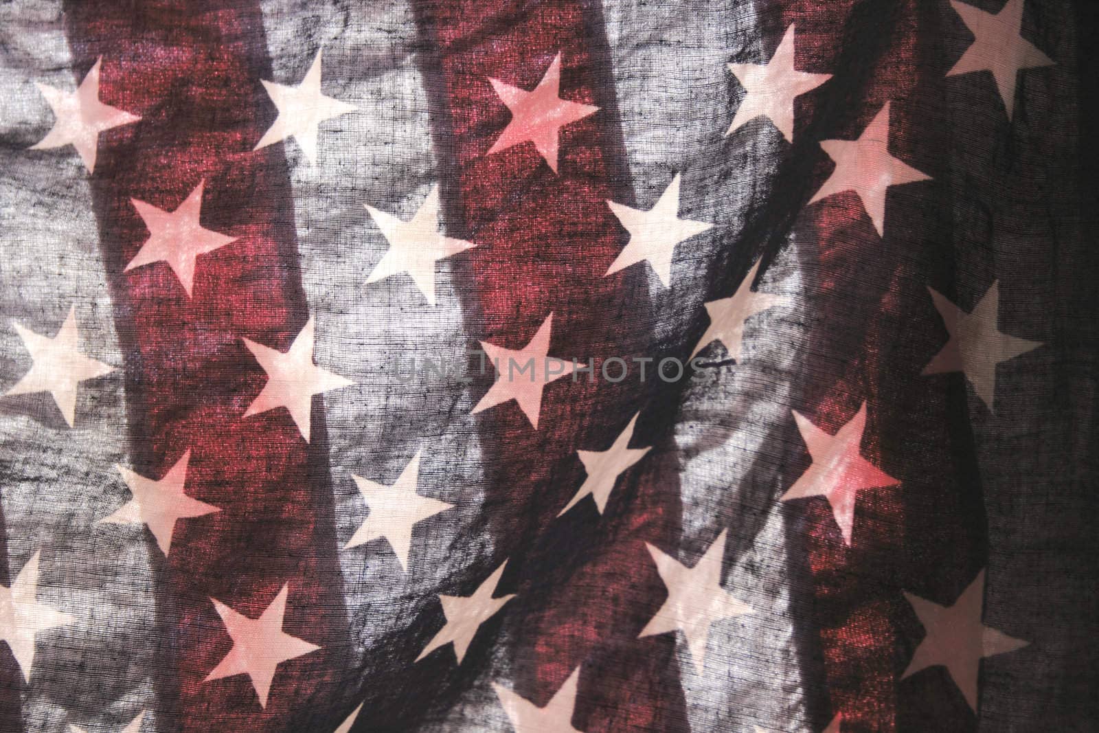 backlit old American flag showing stars over stripes
