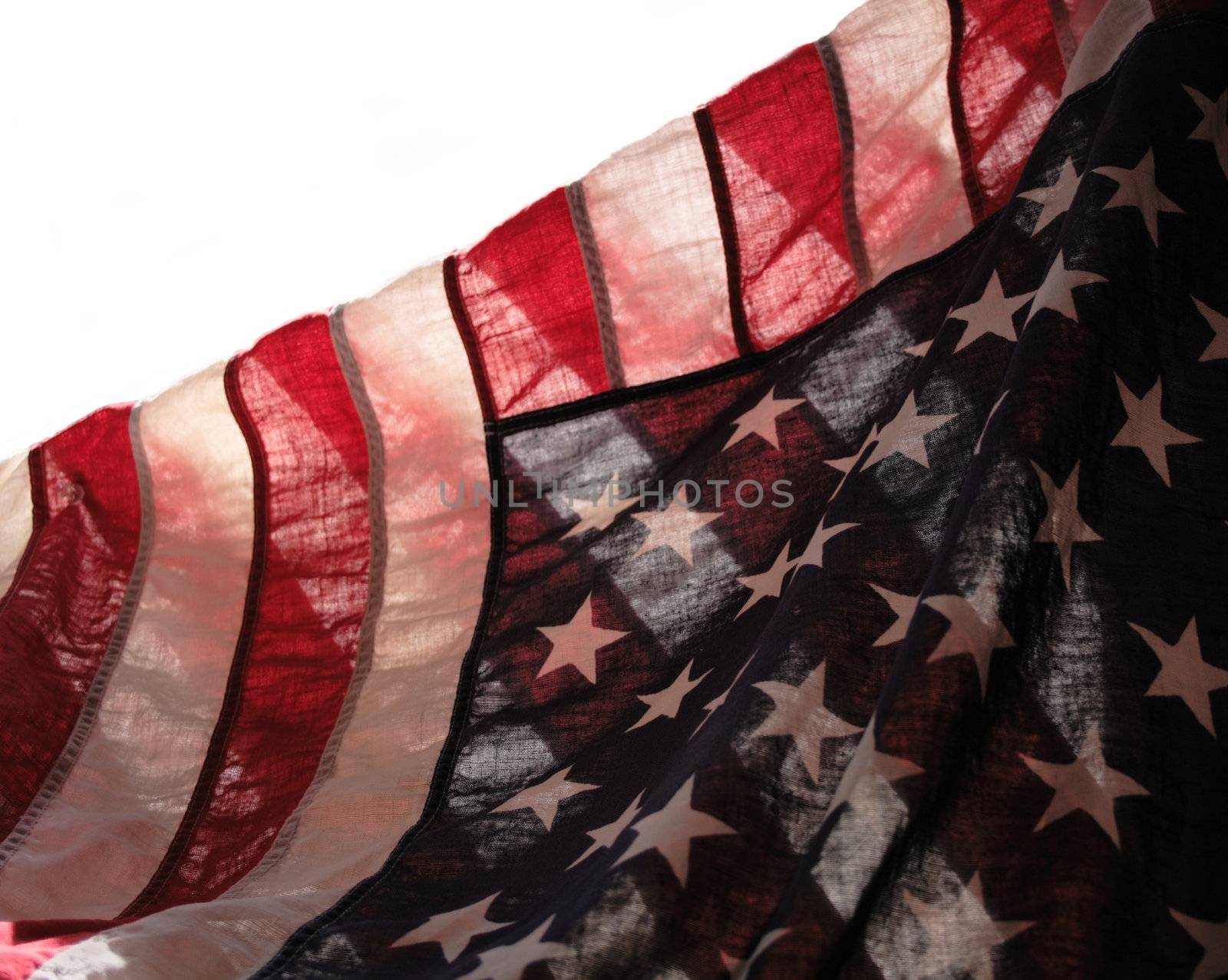backlit old American flag showing stars over stripes