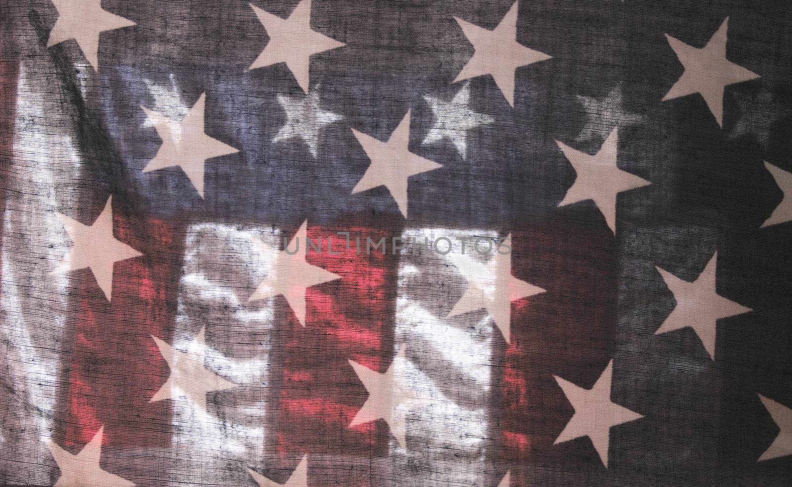 backlit old American flag showing stars over stripes