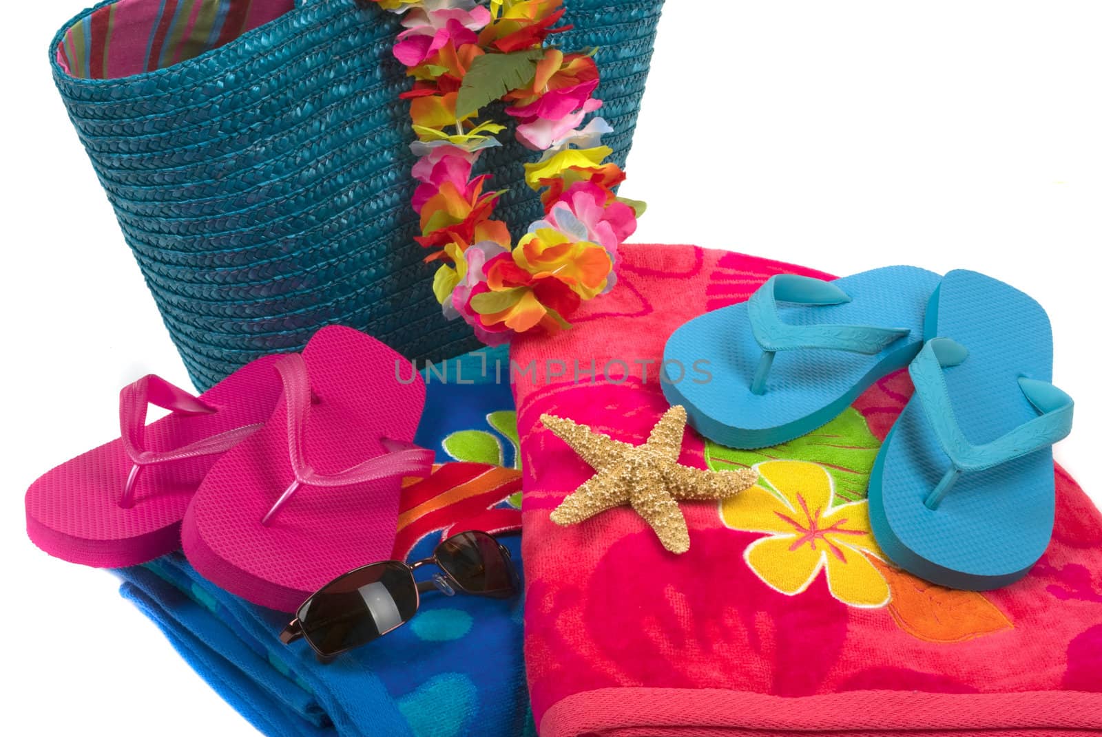 Colorful summer beachwear, flipflops, hat, orchids, sunglasses, towels, beach bag, and starfish