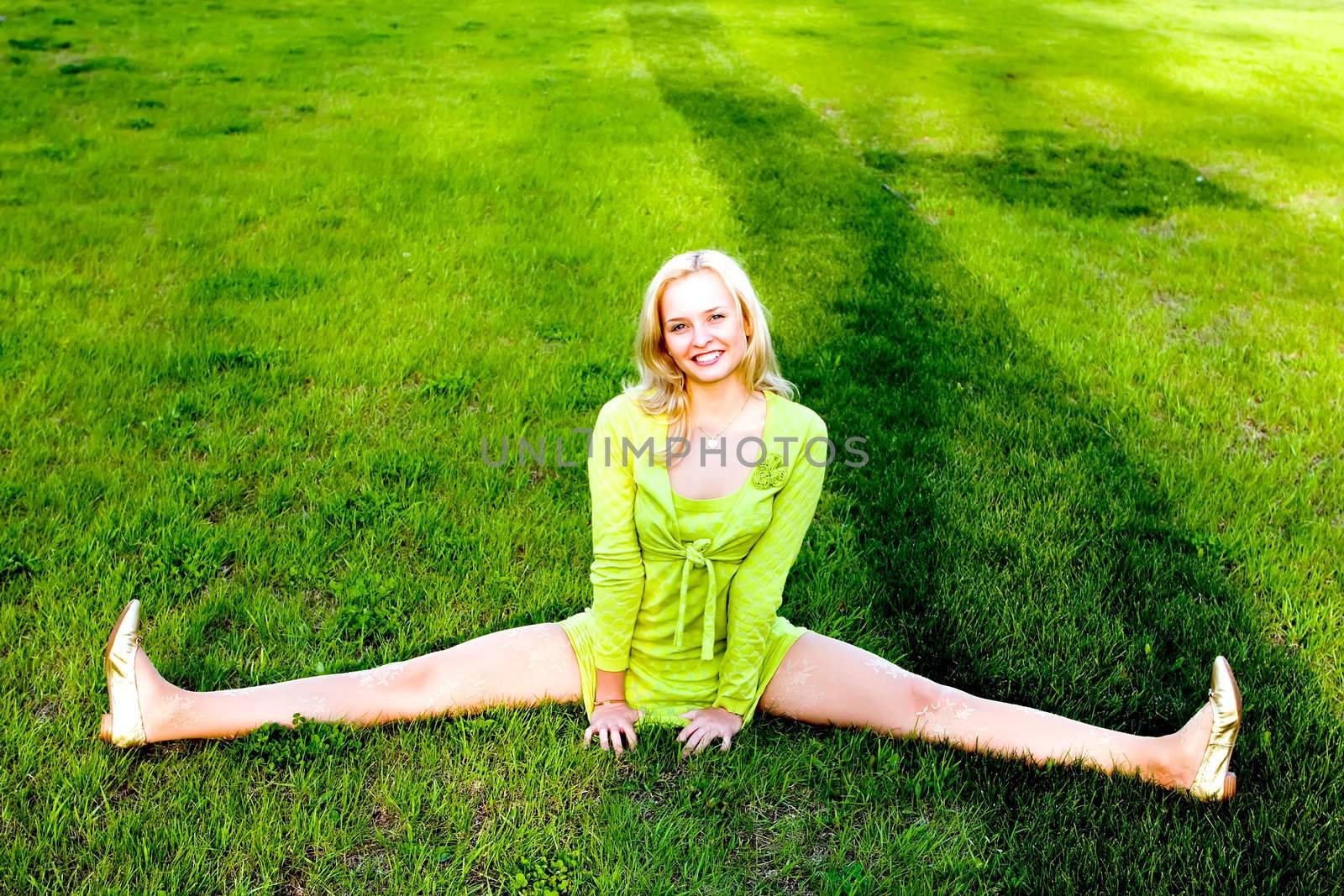 The young girl carrying out gymnastic exercise on a grass