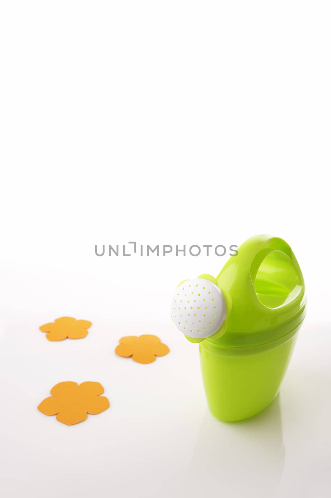 Watering can on white background with orange paper flower