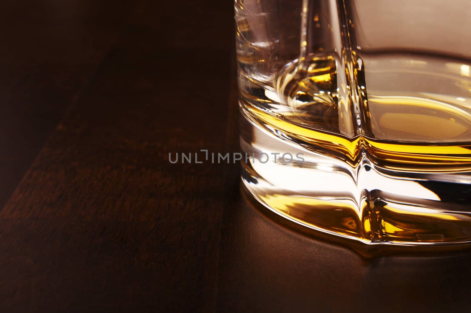 Part of the whiskey glass over a dark wooden table