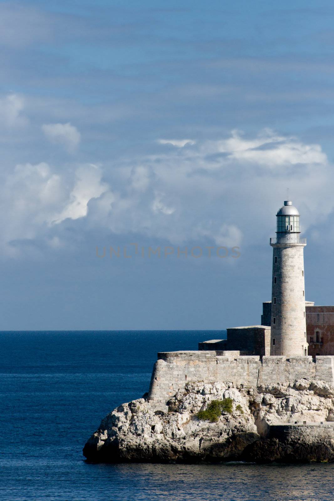 Old lighthouse on the rock at El Morro with a blue cloudy sky in a background. Havana, Cuba.