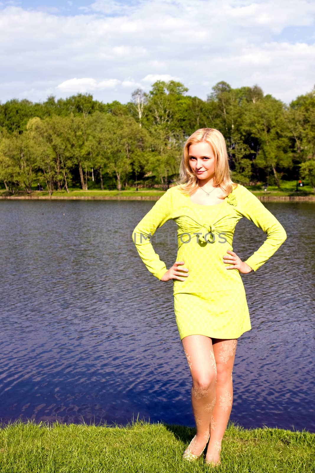 The beautiful girl stands on the bank of the river