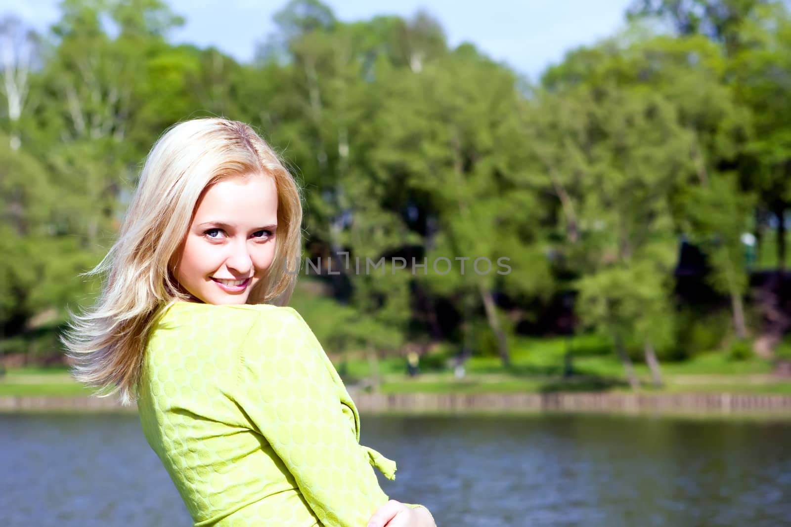 The beautiful girl stands on the bank of the river