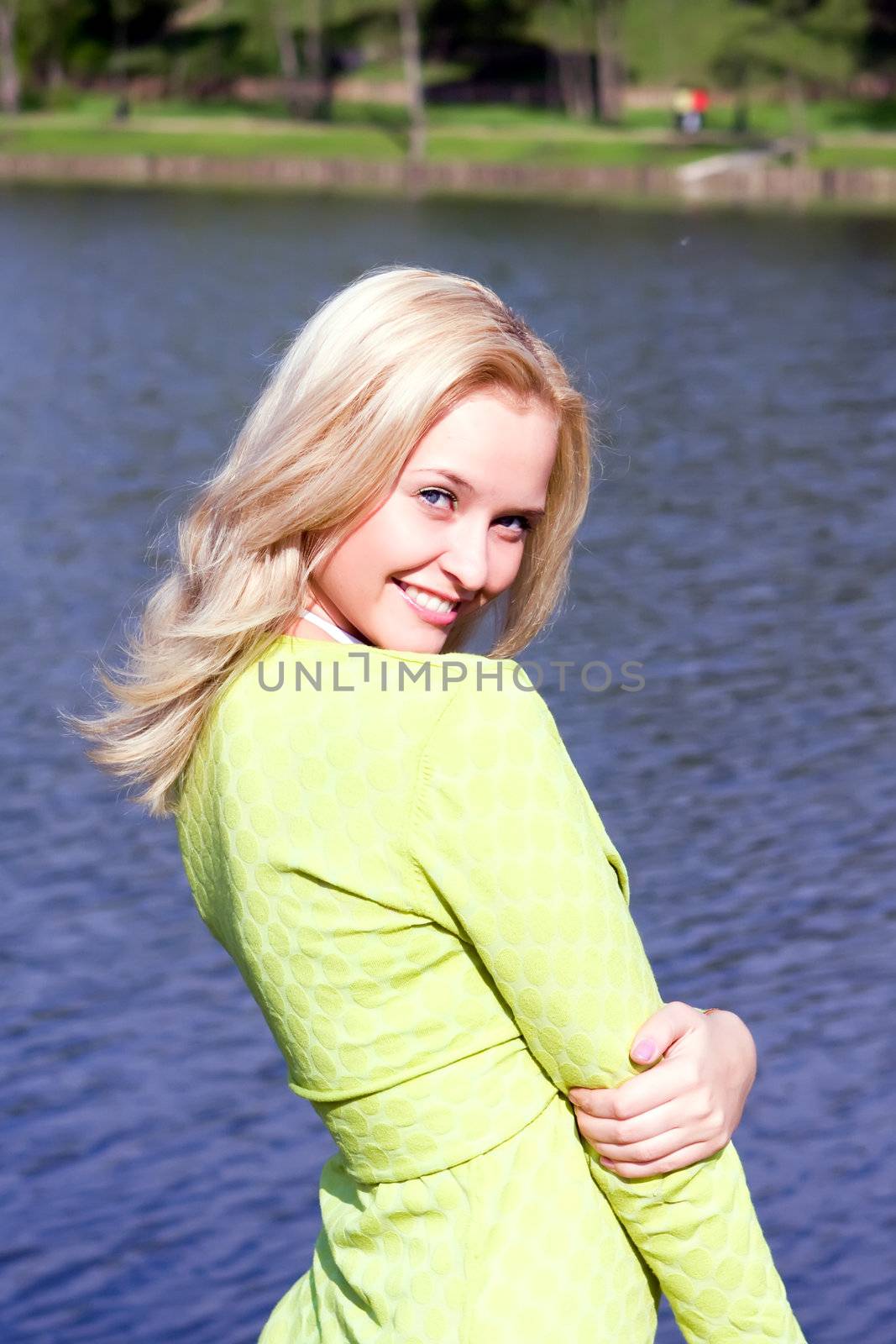 The beautiful girl stands on the bank of the river