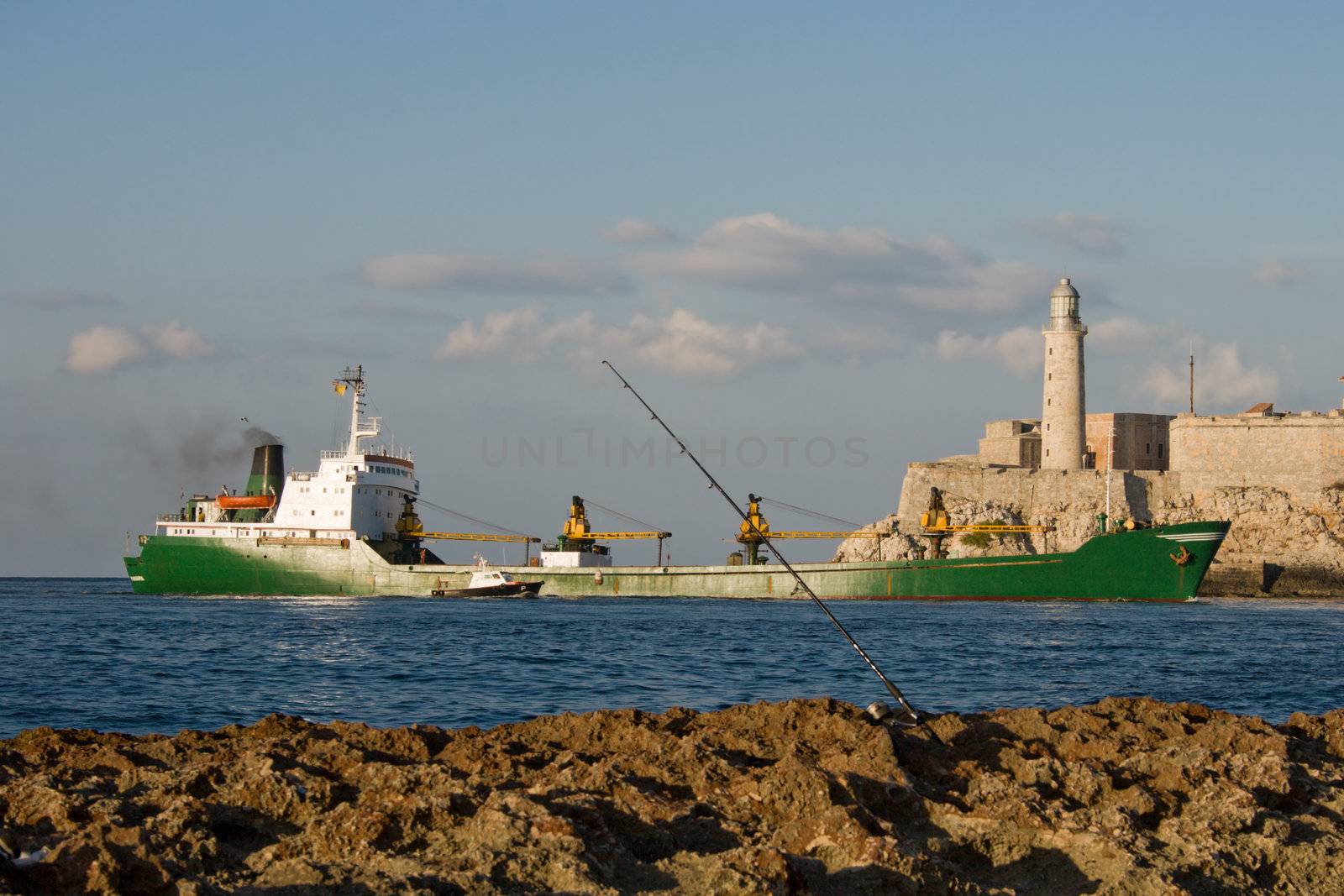 Cargo ship entering the bay of Havana with the lighthouse of El Morro in a background