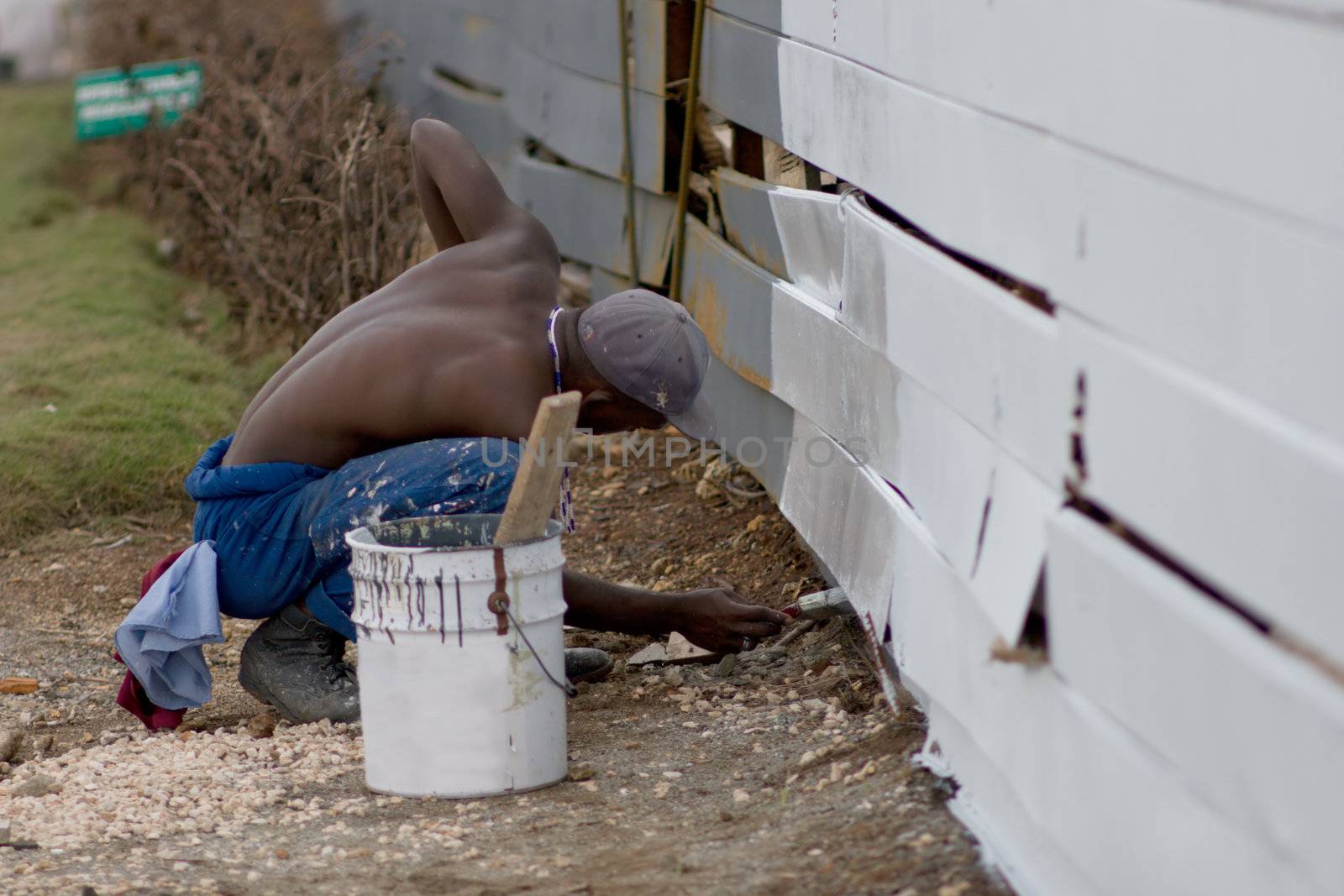 A man is painting a fence with white color. January 2008, Center of Havana, Cuba.