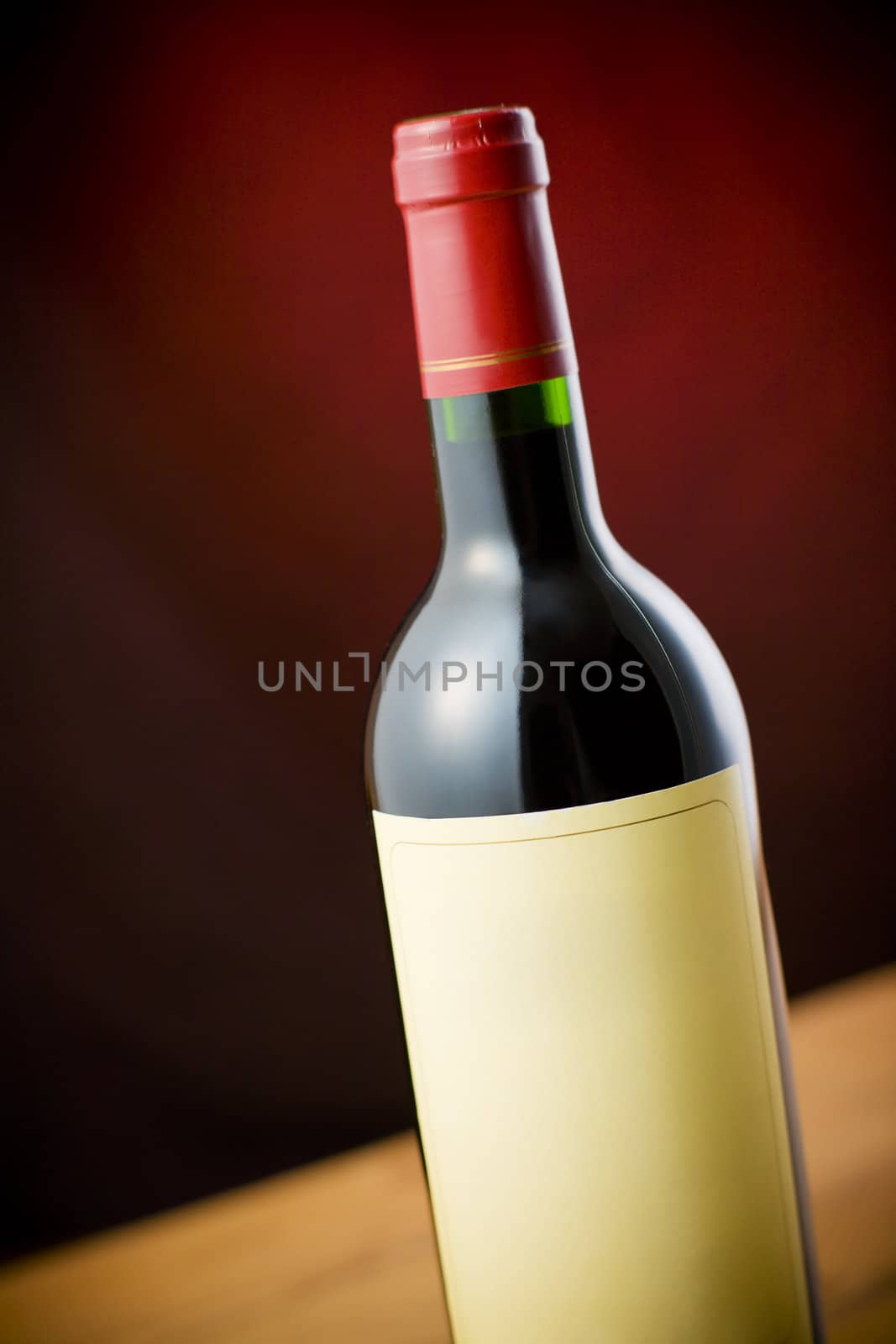 Red wine bottle on wooden table over dark red background