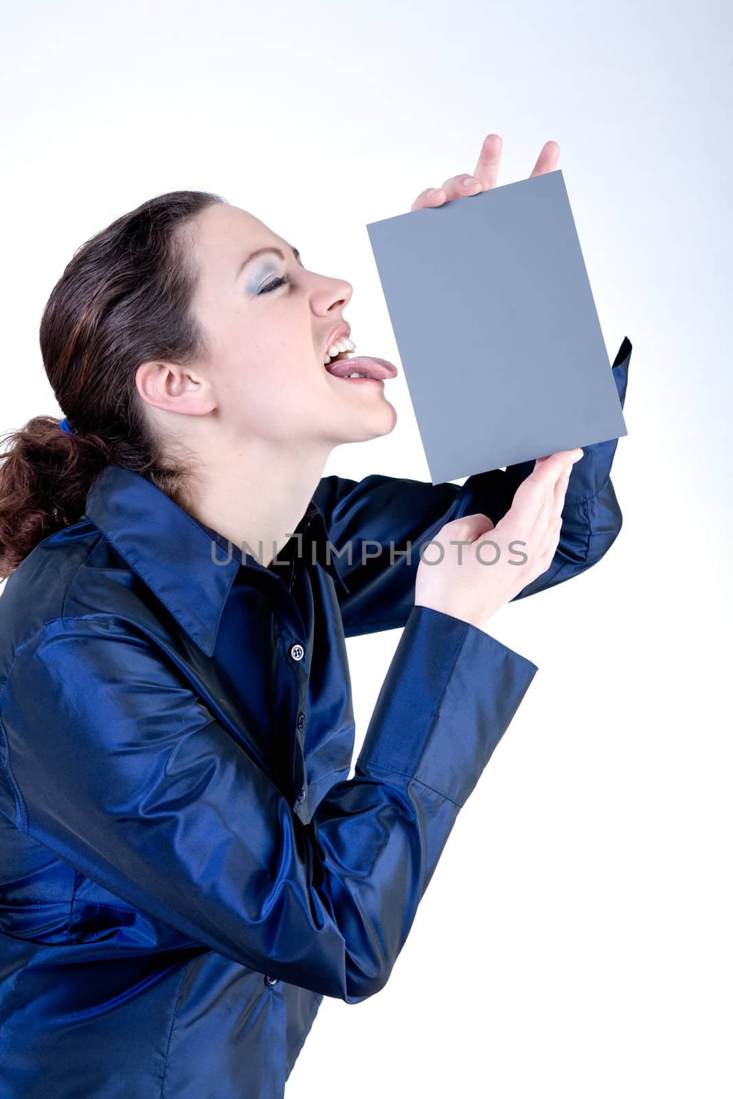 Portrait of a woman with long curly hair putting her tongue against a grey card