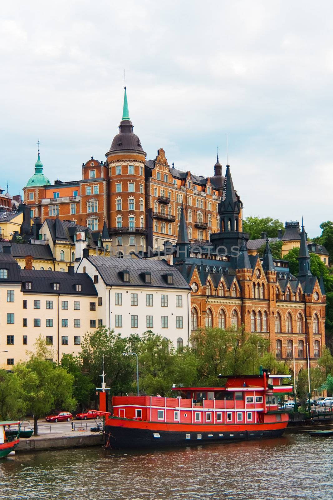 Red boat on water near old nordic city buildings