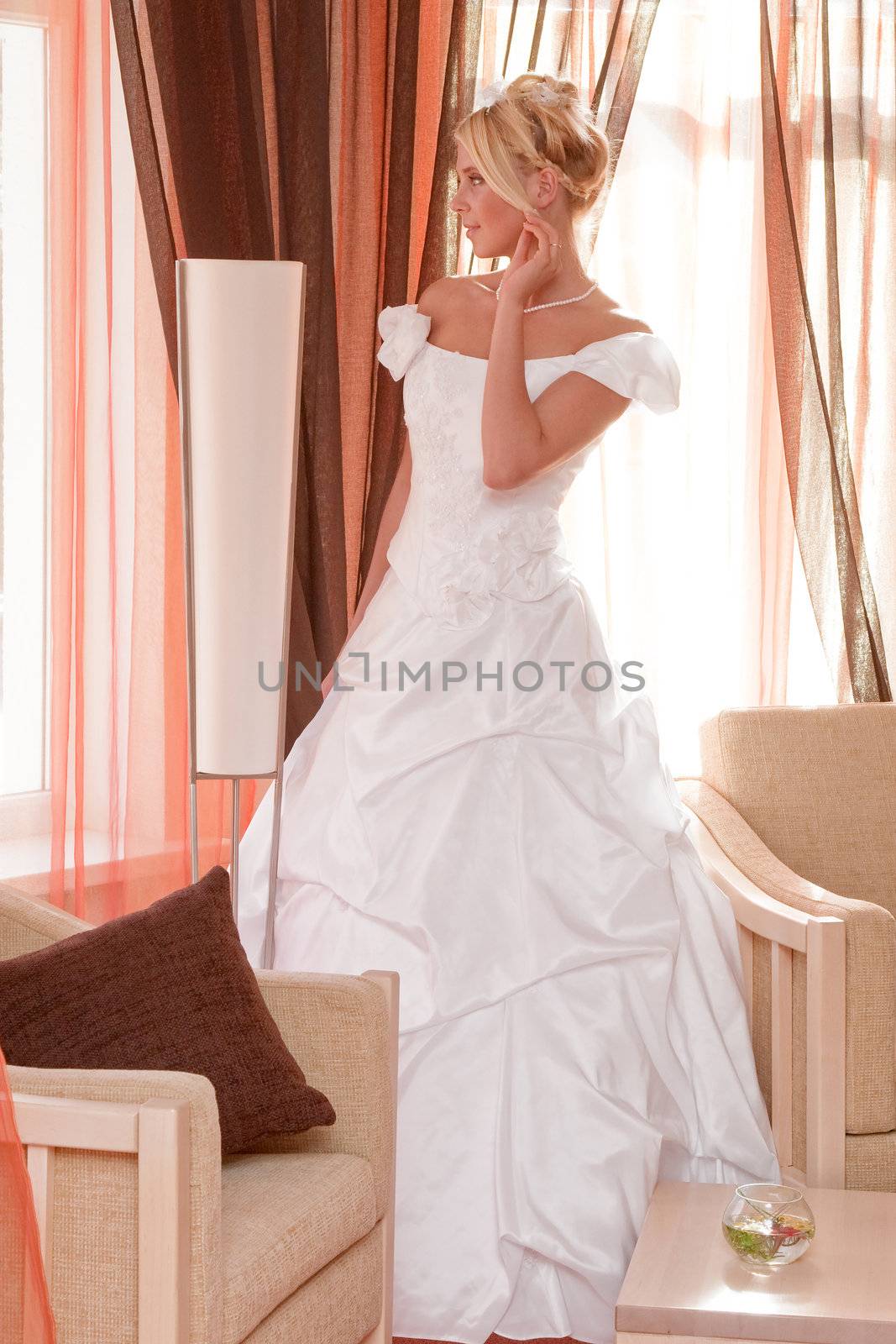 Beautiful blonde bride in white dress in interior