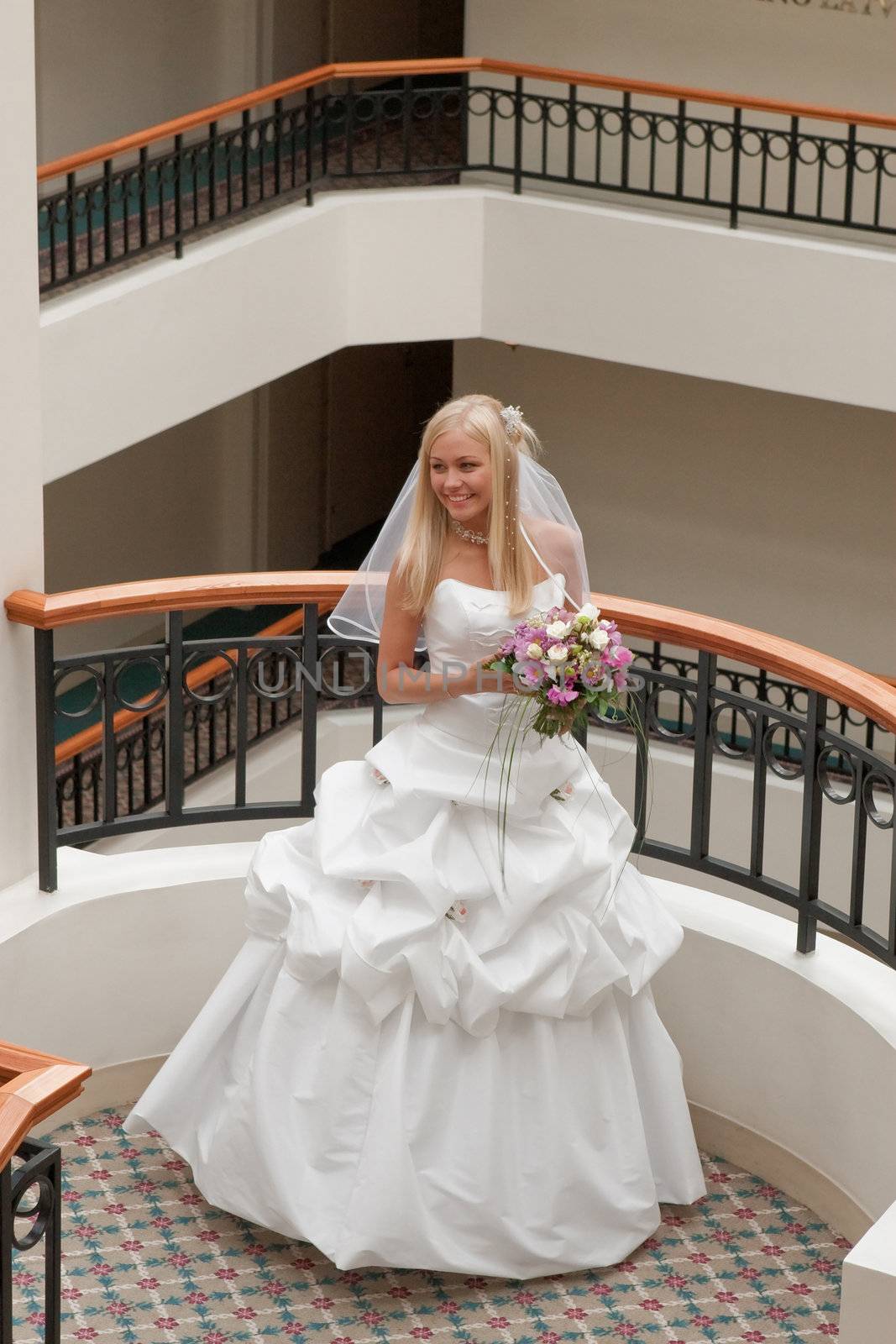 Beautiful blonde bride with bunch of flowers in the gallery