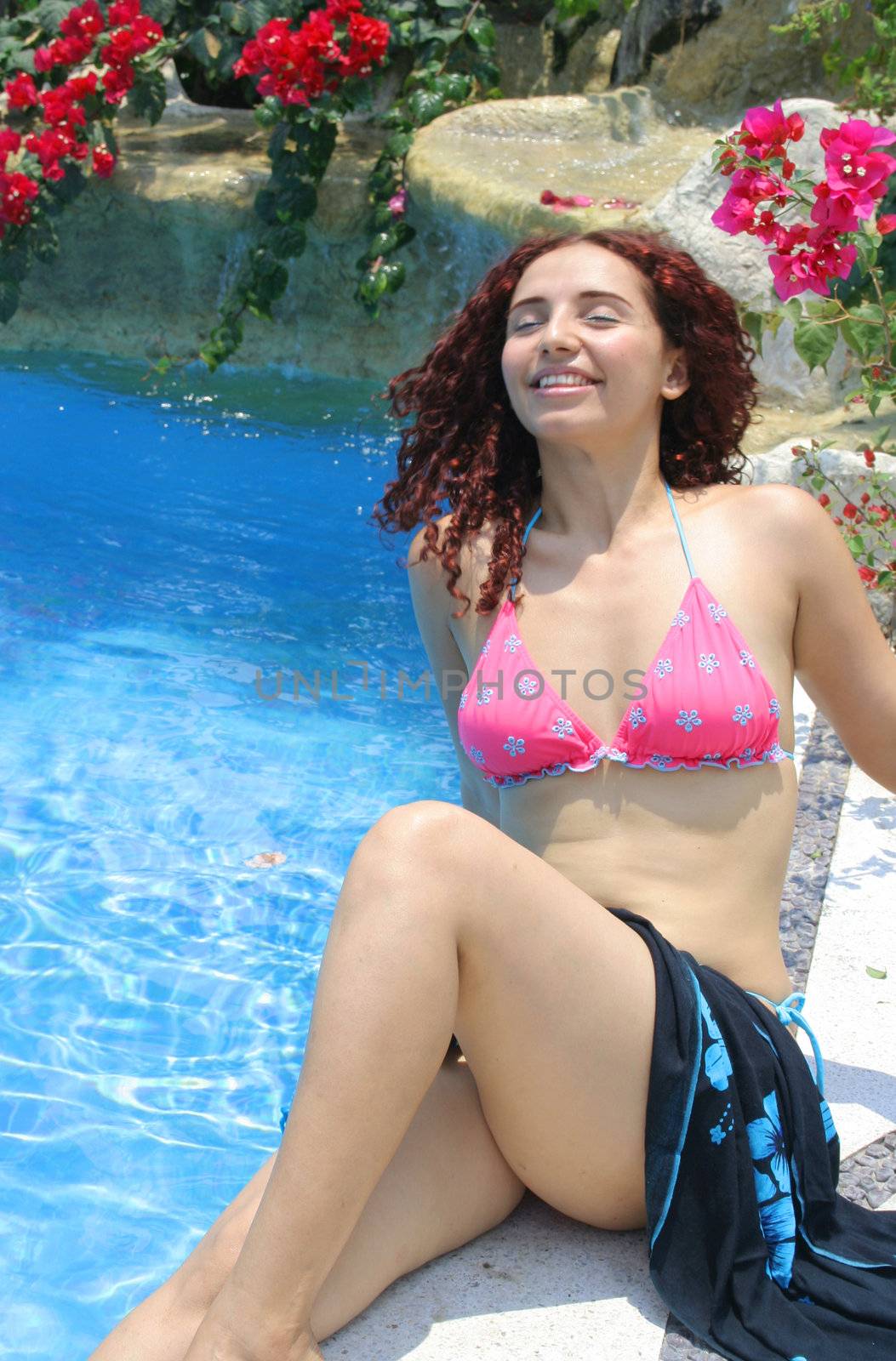 Beautiful youg woman poolside enjoying cool water and sunshine
