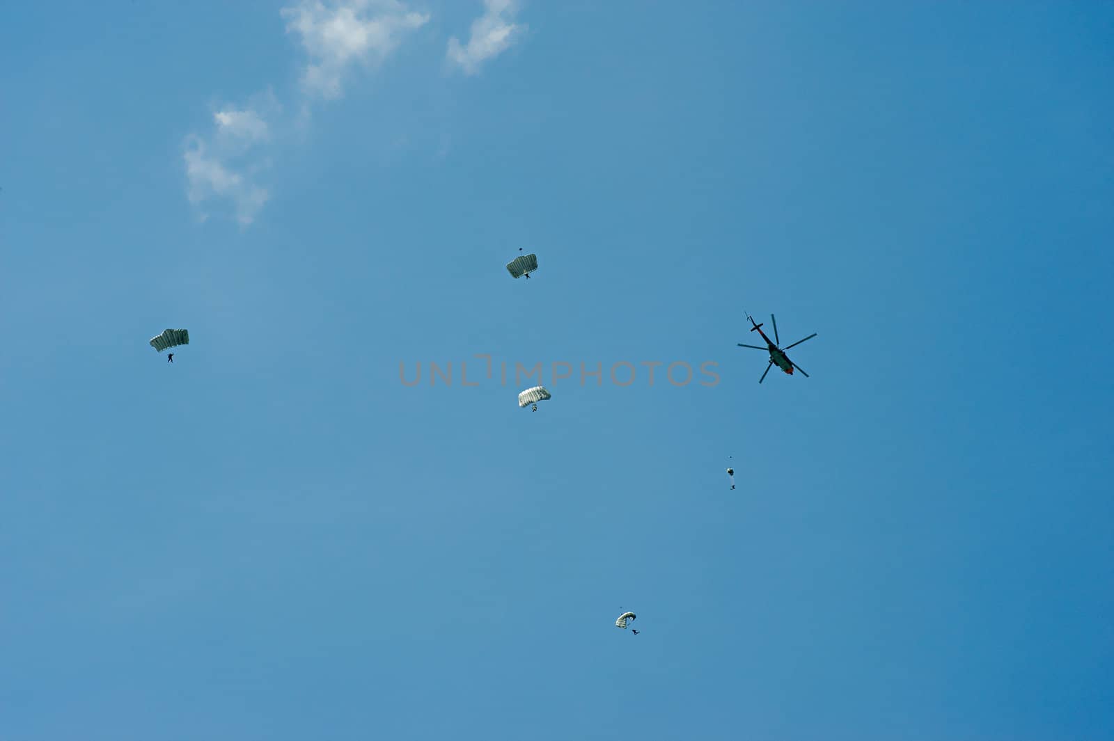 Tandem paragliders and helicopter in the sky
