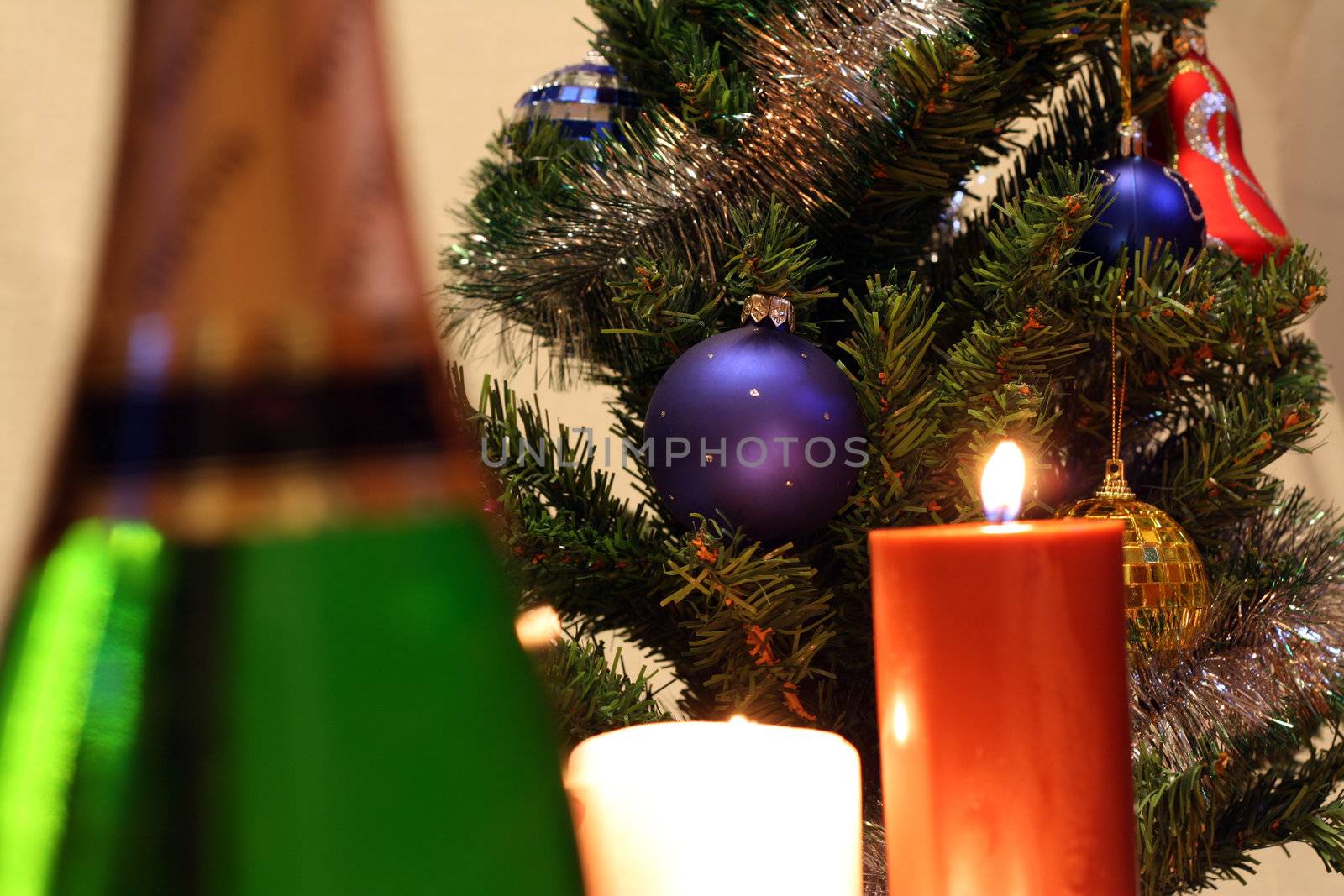 New Year's or Cristmas Tree, burning candles and bottle of champagne out of focus