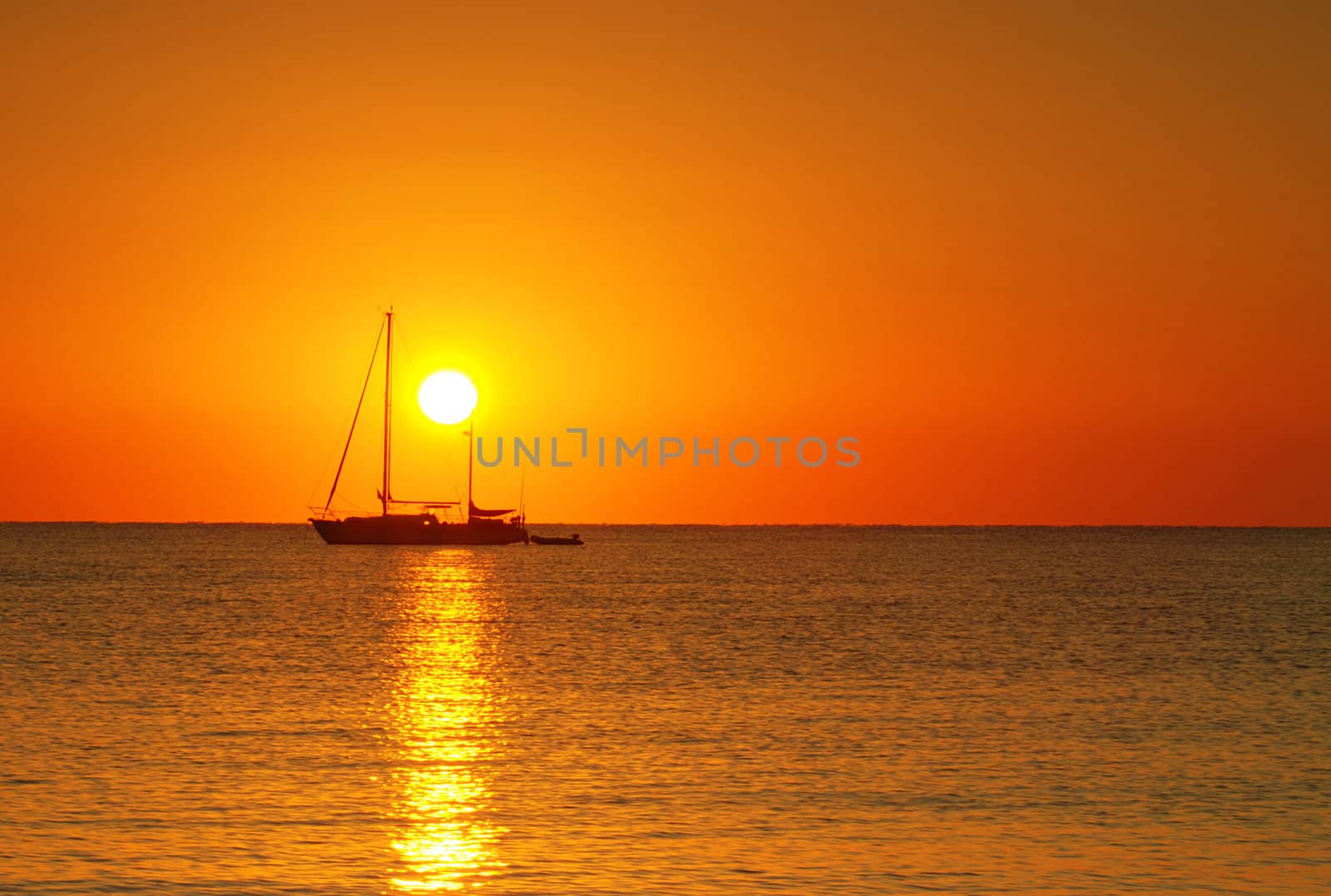 Sailing boat silhouette and golden sunrise over the ocean