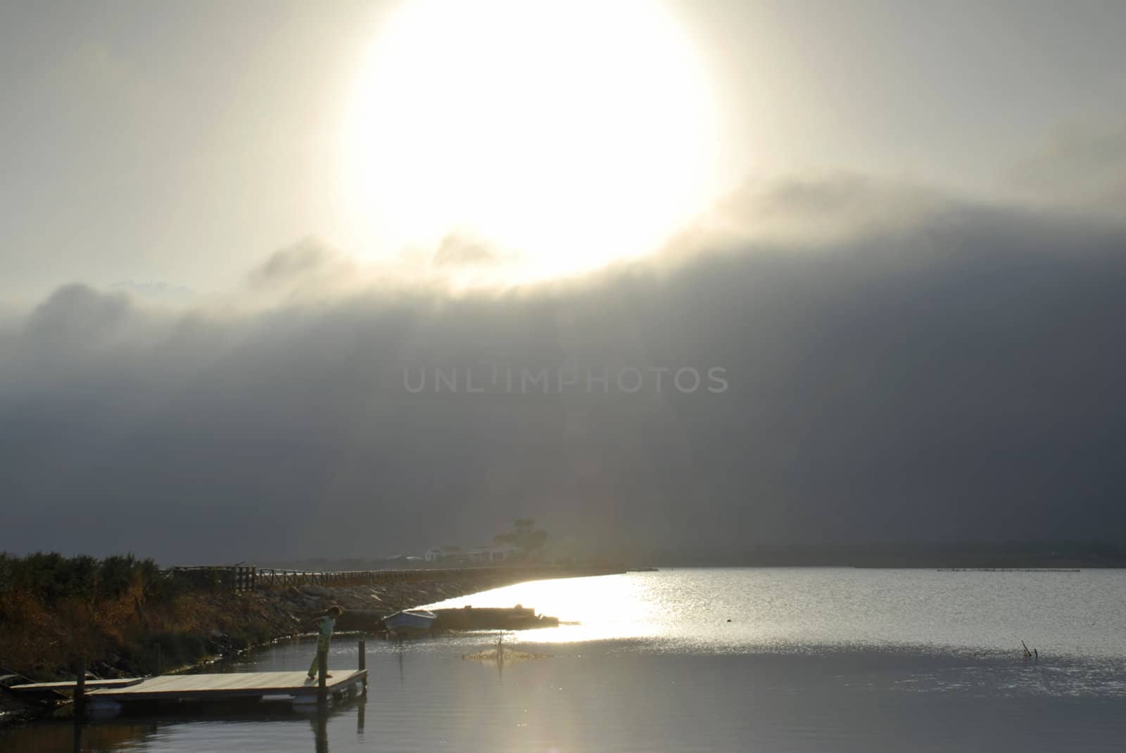 Girl is standing on the pier and watching the storm coming in the harbour