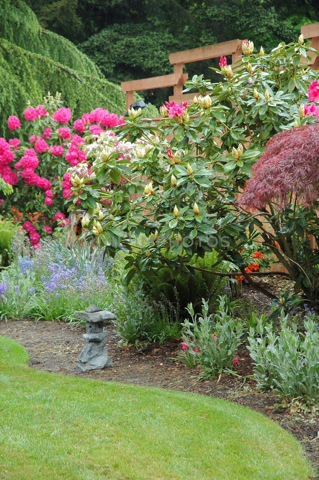 A beautiful landscaped yard with flowers, plants and trees.
