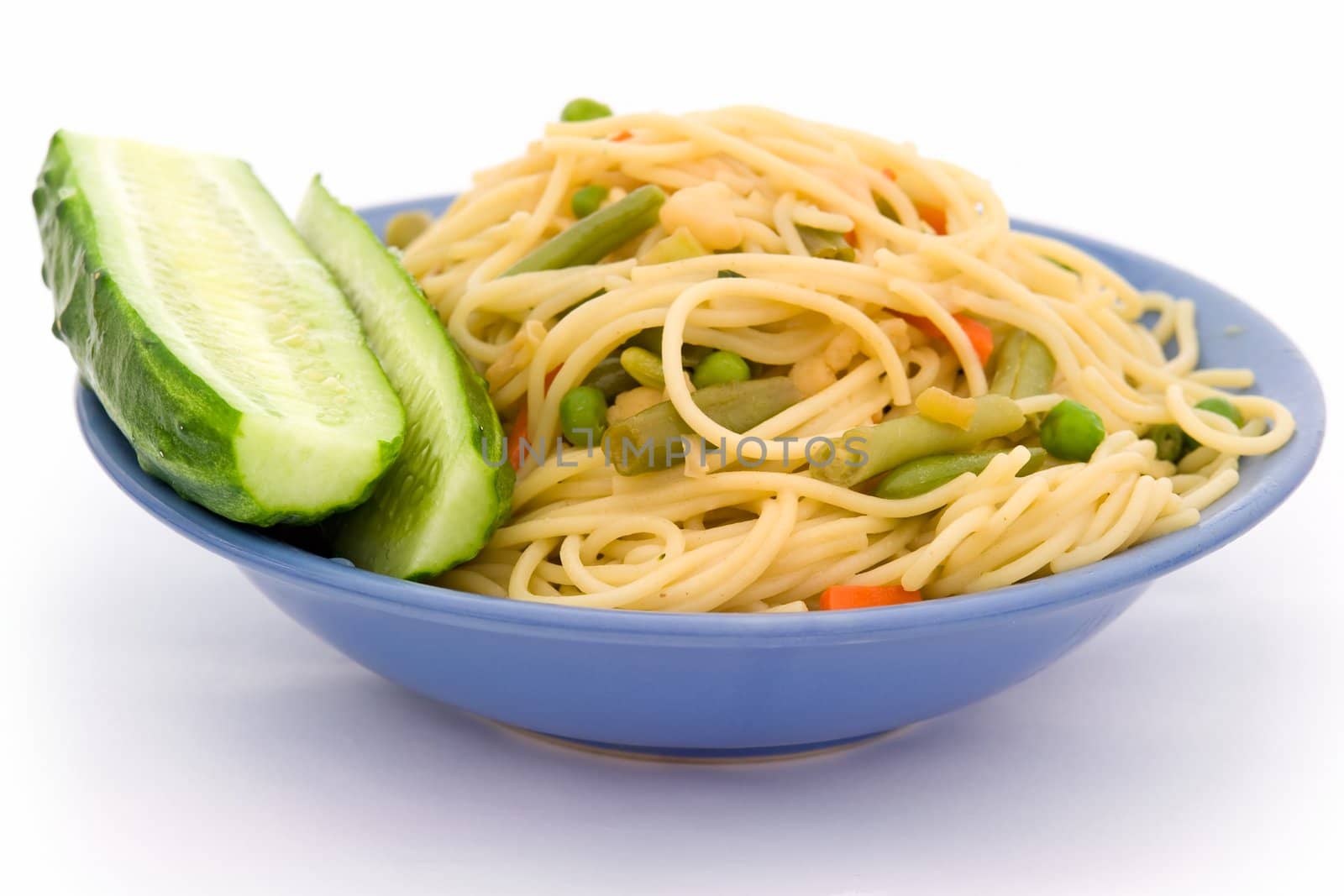 Spaghetti and green cucumber in a blue plate on a white background