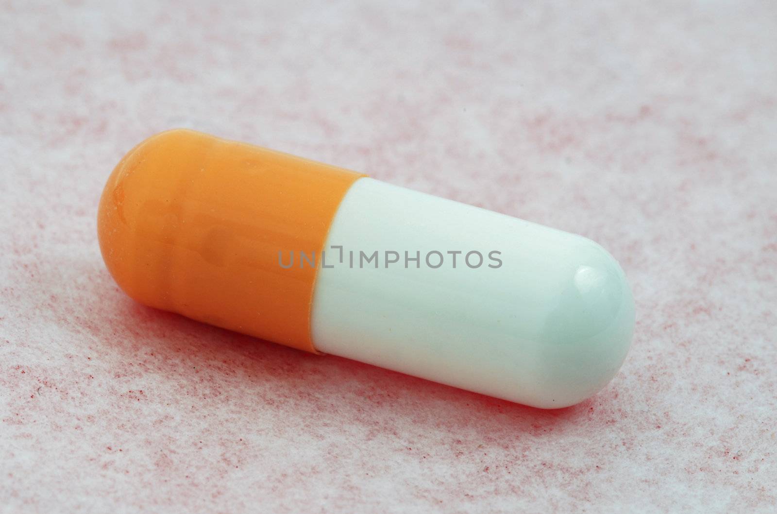 Single medical capsule macro isolated on the pink surface