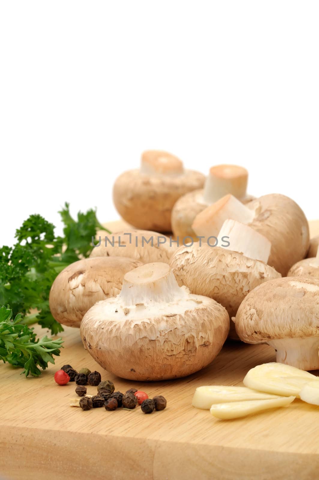Raw ingredients on a wooden cutting board : mushrooms, parsley, whole pepper and garlic